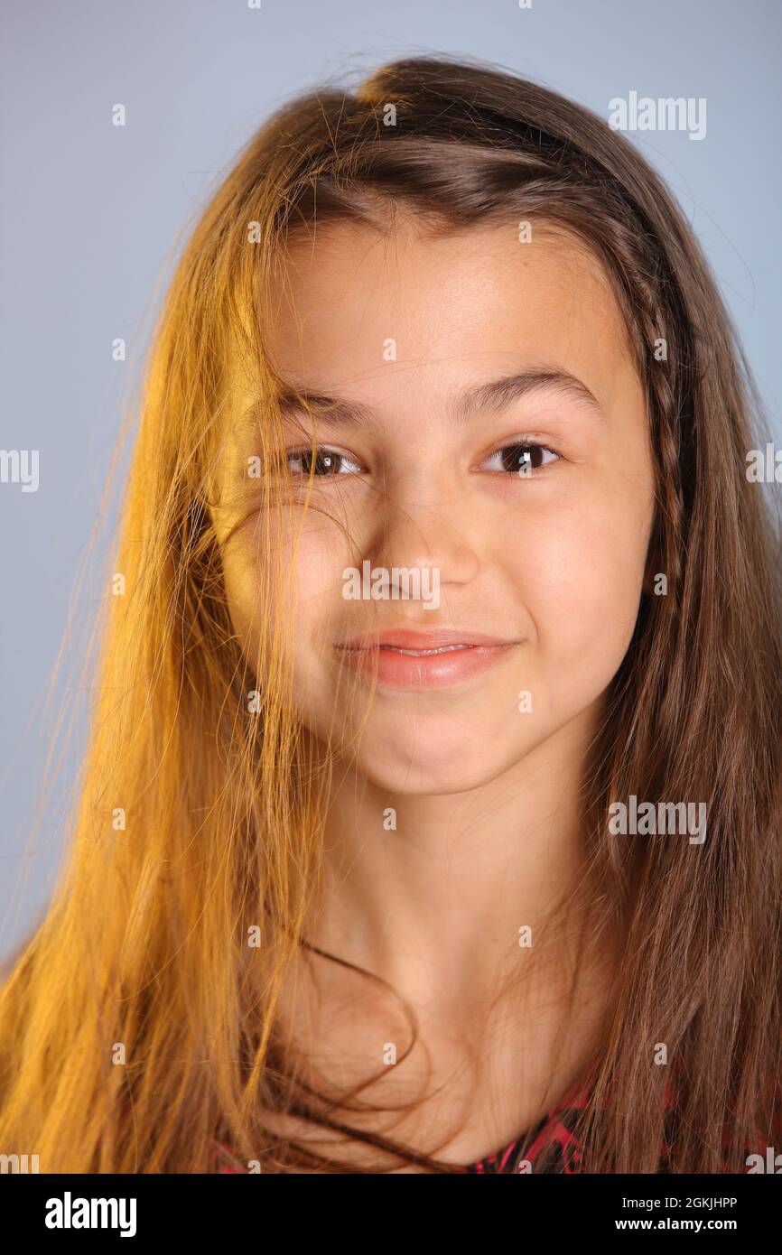 Nahaufnahme Porträt eines hellen niedlichen dunkelhaarigen Teenager-Mädchen 12 Jahre alt in einem lila Kleid, ihre braunen Augen lachen und sehen Auge in Auge. Stockfoto