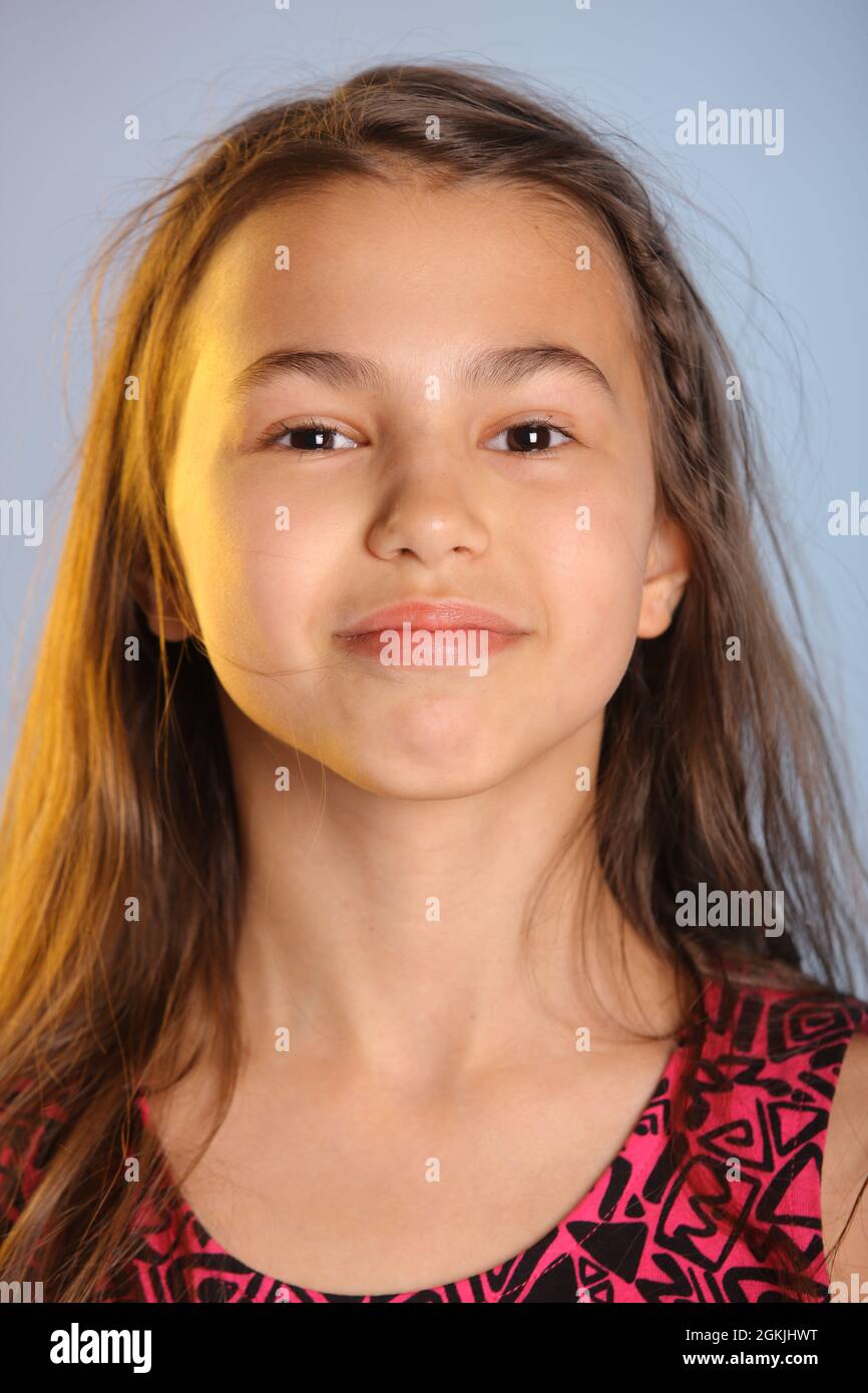 Nahaufnahme Porträt eines hellen niedlichen dunkelhaarigen Teenager-Mädchen 12 Jahre alt in einem lila Kleid, ihre braunen Augen lachen und sehen Auge in Auge. Stockfoto