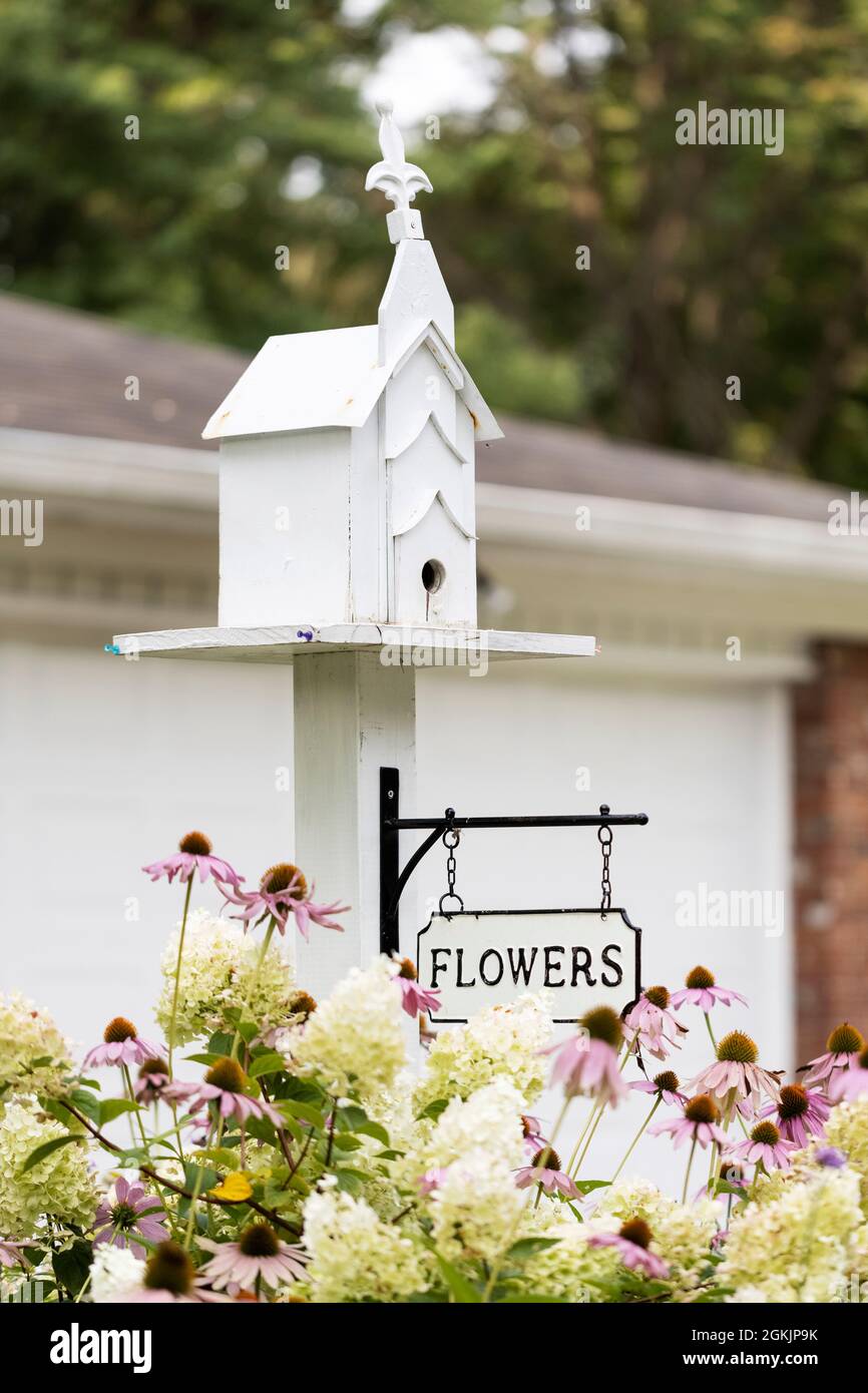 Ein Vogelhaus, das wie eine Kirche mit einem Blumenschild in einem Garten in Indianapolis, Indiana, USA, gestaltet wurde. Stockfoto