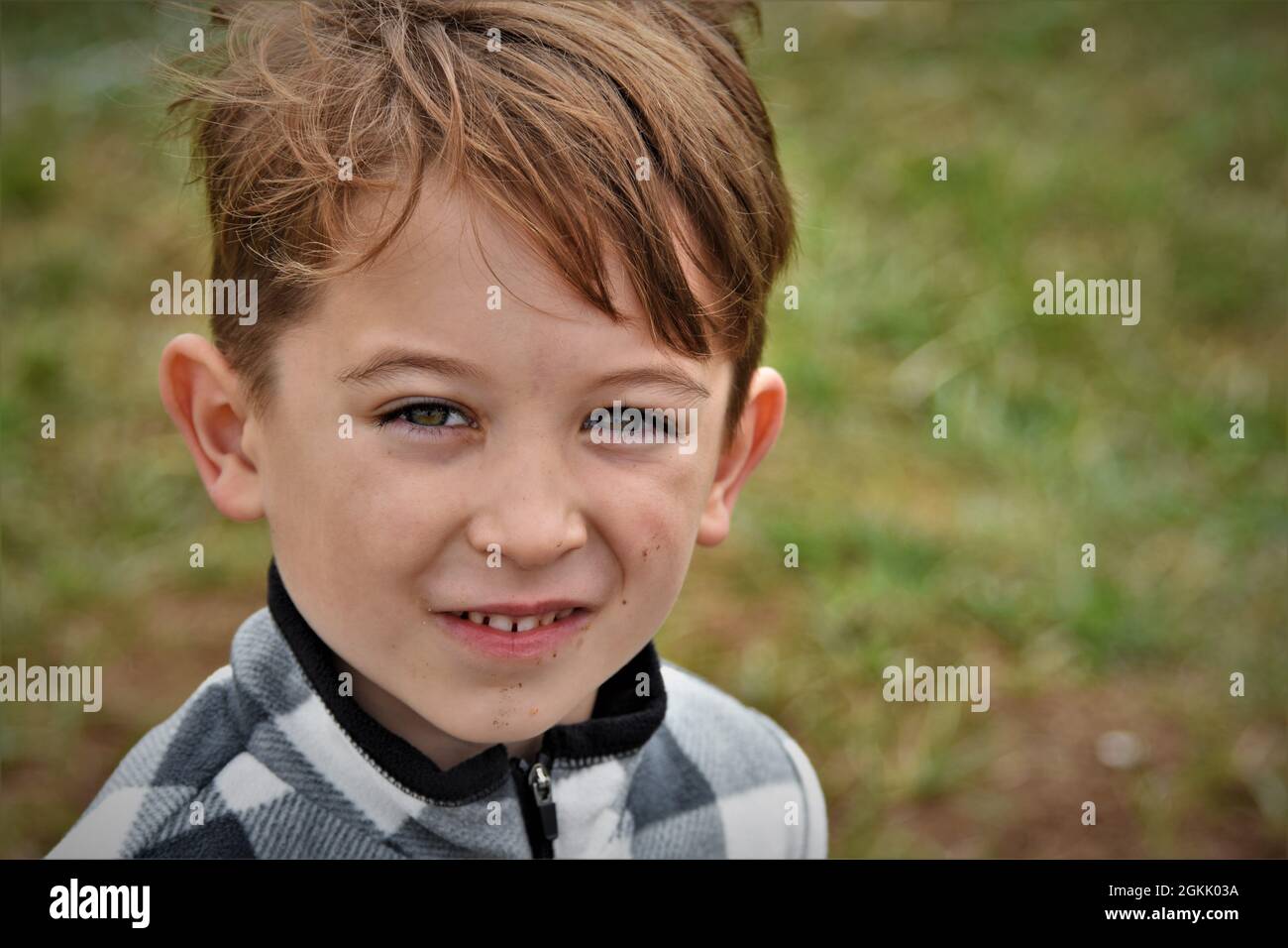 Kaukasischer Junge, der am Spieltag für seine Schwester auf einem sonnigen Fußballfeld die Kamera anschaut Stockfoto