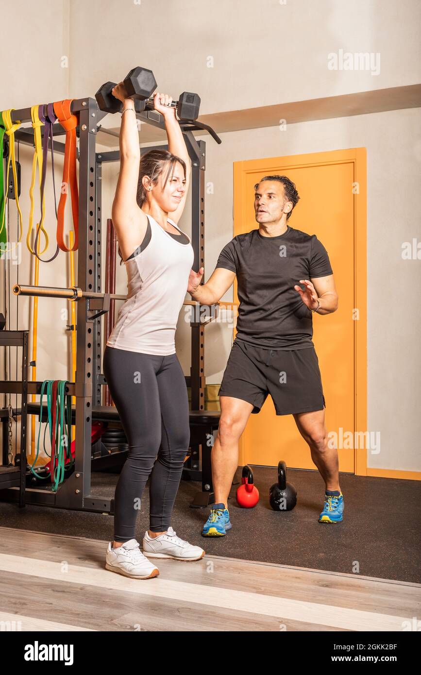 Frau macht Schultertraining mit Hanteln im Fitnessstudio Stockfoto
