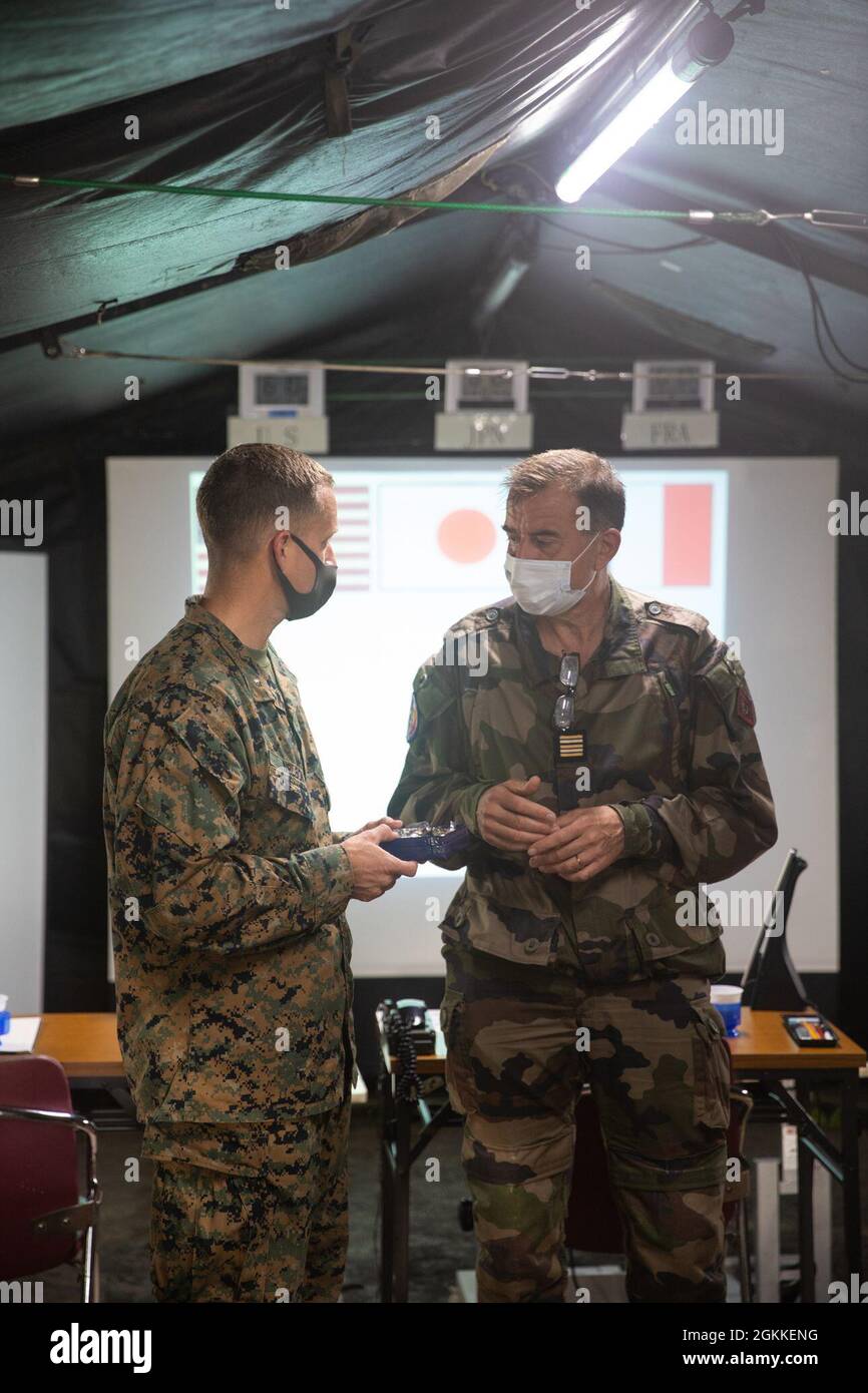 Oberstleutnant Jeremy Nelson, Kommandeur der Seestreitkräfte (links) und Oberstleutnant Henry Marcaillou, Kommandant der französischen Bodentruppen für die Übung, tauschen Geschenke aus, die die Fertigstellung der Jeanne D’Arc 21 im Kirishima Manövergebiet, Japan, am 16. Mai 2021 fortsetzen. Die Lehren und Praktiken, die wir mit unseren japanischen, französischen und australischen Verbündeten während der ARC-21 teilen, machen uns alle besser in der Lage, auf Krisen im gesamten Indo-Pazifik zu reagieren, sei es bei der Verteidigung Japans, der Reaktion auf Notfälle in anderen Teilen der Region oder auch wenn wir zu humanitären Hilfsmaßnahmen oder Katastrophenhilfe aufgerufen werden. Stockfoto