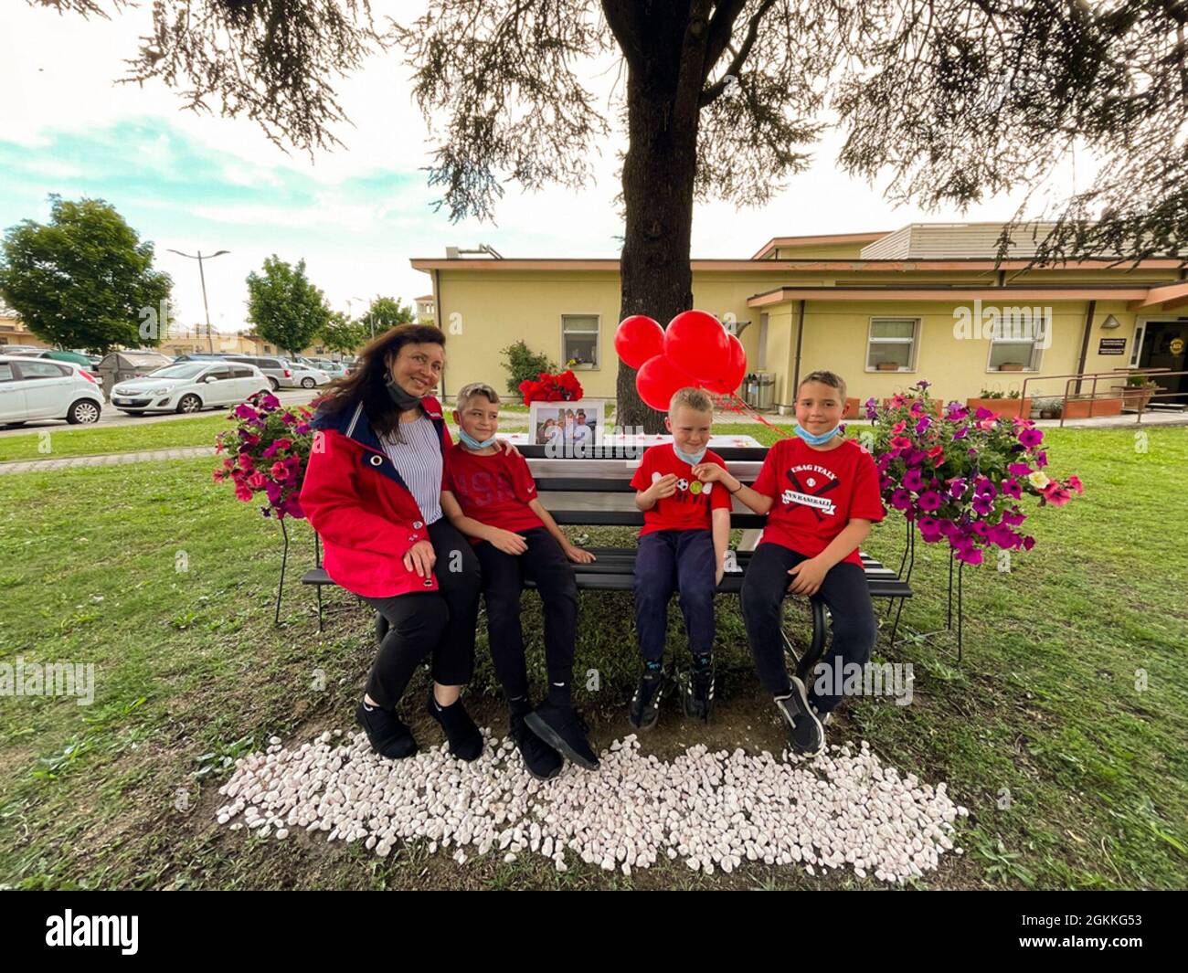 Brian, Matthew und Thomas, Jr. Ehler und die Witwe Tatiana Soldaenko, sitzen auf der Gedenkbank für Thomas Ehler, bei einer Gedenkfeier am 17. Mai 2021 im USAG Italy Army Community Service, Vicenza, Italien. Stockfoto