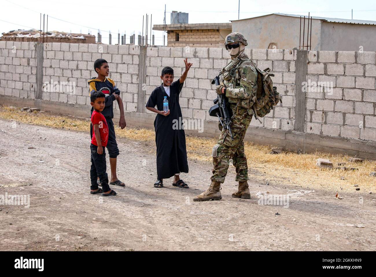 Soldaten der US-Armee halten während einer Routinepatrouille am 17. Mai in einem syrischen Dorf an, um über ein örtliches Ölauslaufen zu diskutieren. Während des Besuches hatten lokale Kinder freundschaftliche Interaktionen mit Soldaten, die die Verbundenheit und das Vertrauen zwischen der lokalen Gemeinde und dem US-Militär zeigen. Stockfoto