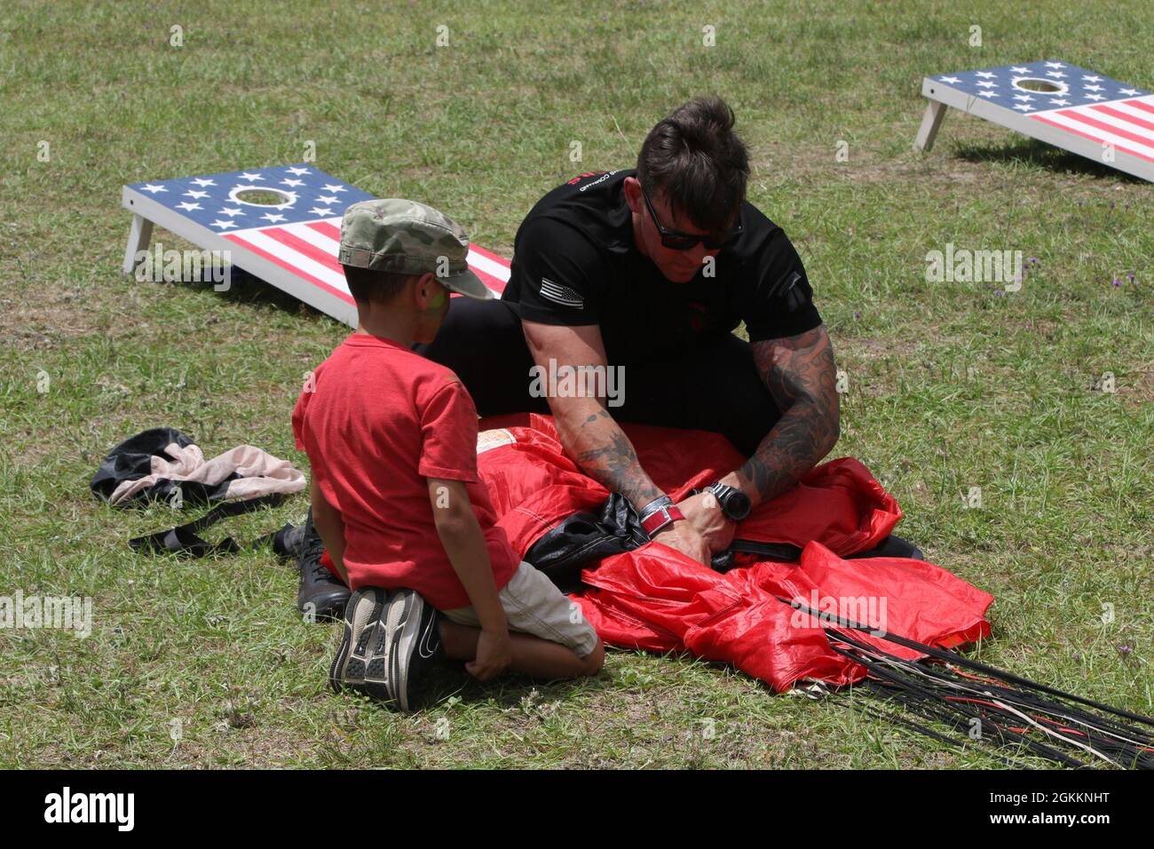 US Army Sgt. Ryan Tremblay, der dem Army Special Operations Command, einem Mitglied der Black Dolgers, dem offiziellen Fallschirmdemonstrationsteam des U.S. Army Special Operations Command, zugewiesen wurde, lehrt ein Kind während des Marne Week Family Day, am 19. Mai 2021, einen Fallschirm auf Fort Stewart, Georgia, richtig einzupacken. Die Marne Week bringt derzeit im Dienst befindliche Dogface-Soldaten, Veteranen, Familienmitglieder und die Gemeinschaft zusammen, um das Vermächtnis der Division zu feiern. Stockfoto