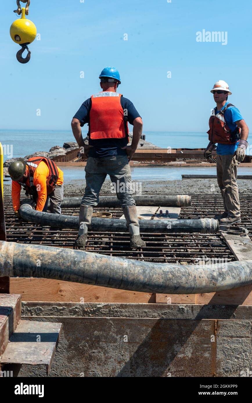 Dean Marine & Excavating, Inc., Subunternehmer des U.S. Army Corps of Engineers im Buffalo District, arbeitet an Betongiessarbeiten, um einen 600 Meter langen Teil des Rochester Harbour East Pier, Rochester, NY, zu reparieren, 19. Mai 2021. Der Hauptzweck des East Pier ist es, den Hafen von Rochester vor schädigender Wellenenergie vom Lake Ontario zu schützen. Etwa 1000 Meter vom östlichen Pier ist stark beschädigt und muss repariert werden. Der Buffalo District vergab eine 73,4 Millionen für die Reparatur von 600 Fuß des stark degradierten 111 Jahre alten Abschnitts des östlichen Piers. Der East Pier von Rochester Harbour wurde 1908 errichtet. Stockfoto