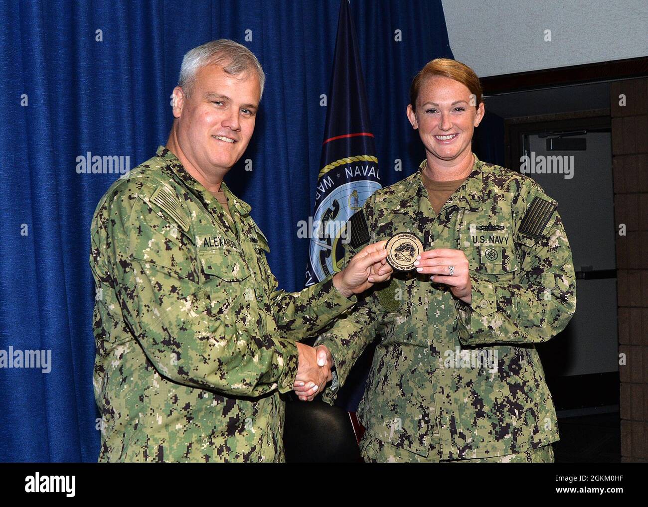 Hinterer Adm. Christopher Alexander, Kommandant des Naval Surface and Mine Warfighting Development Center (SMWDC), übergibt ein Patch für den Instruktor der Kampftaktik (WTI) für Amphibious Warfare (AMW) und gratuliert LT. Krista Hebenstreit während einer WTI-Abschlusszeremonie an Bord der Naval Station San Diego am 21. Mai. Stockfoto