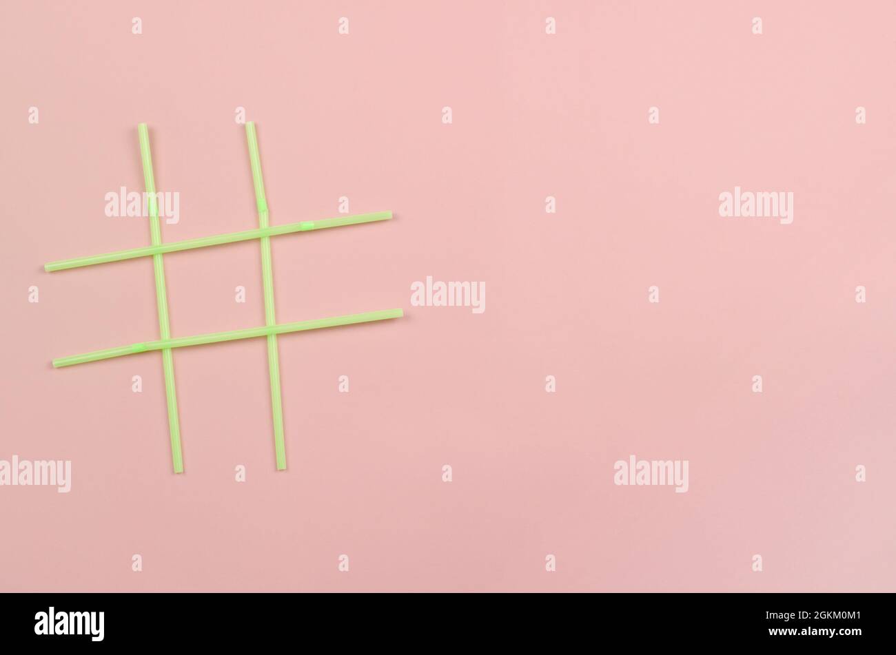 Hashtag-Symbol für grüne Trinkhalme aus Kunststoff auf rosa Hintergrund Stockfoto