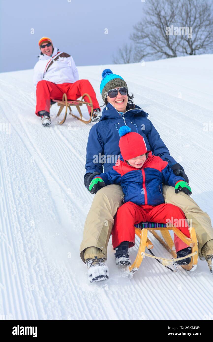 Familie hat Spaß im frischen Schnee an einem sonnigen Wintertag in den österreichischen Alpen Stockfoto