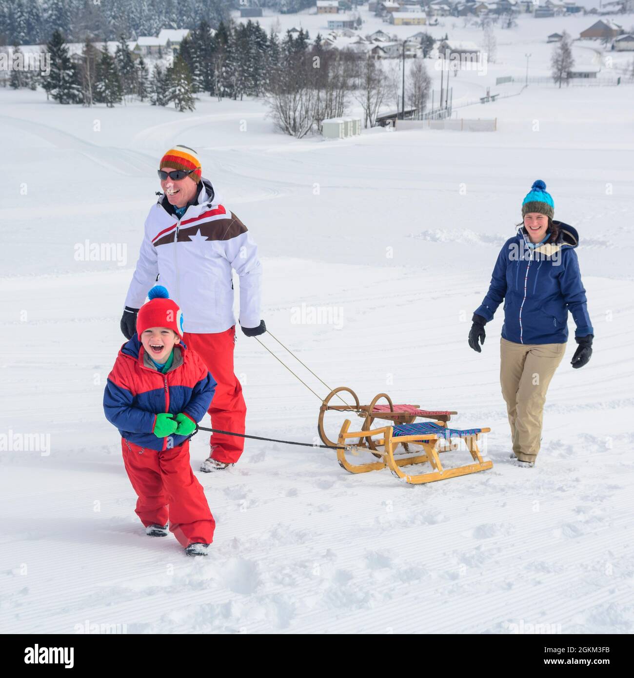 Familie hat Spaß im frischen Schnee an einem sonnigen Wintertag in den österreichischen Alpen Stockfoto