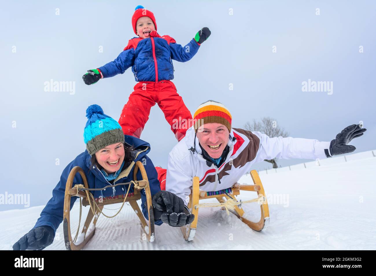 Familie hat Spaß im frischen Schnee an einem sonnigen Wintertag in den österreichischen Alpen Stockfoto