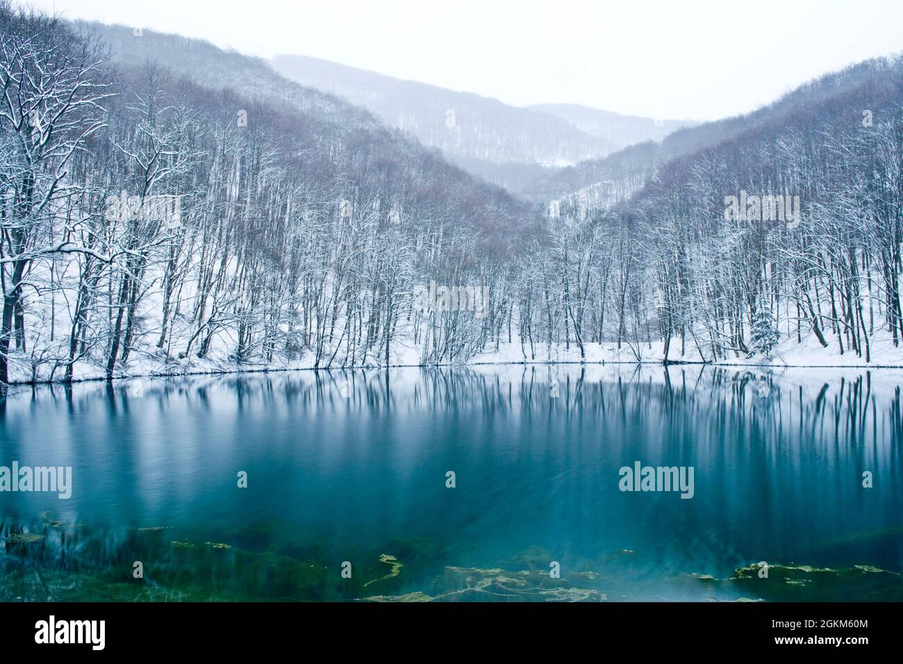 Schöner blauer See zwischen schneebedeckten Bergen im Winter. Szilvásvárad, Ungarn. Stockfoto