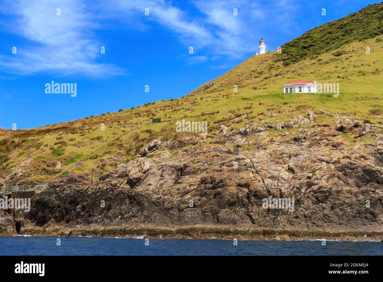 Kap Brett in der Bay of Islands, Neuseeland. Auf der rechten Seite befindet sich ein Leuchtturm und das Department of Conservation Hütte Stockfoto