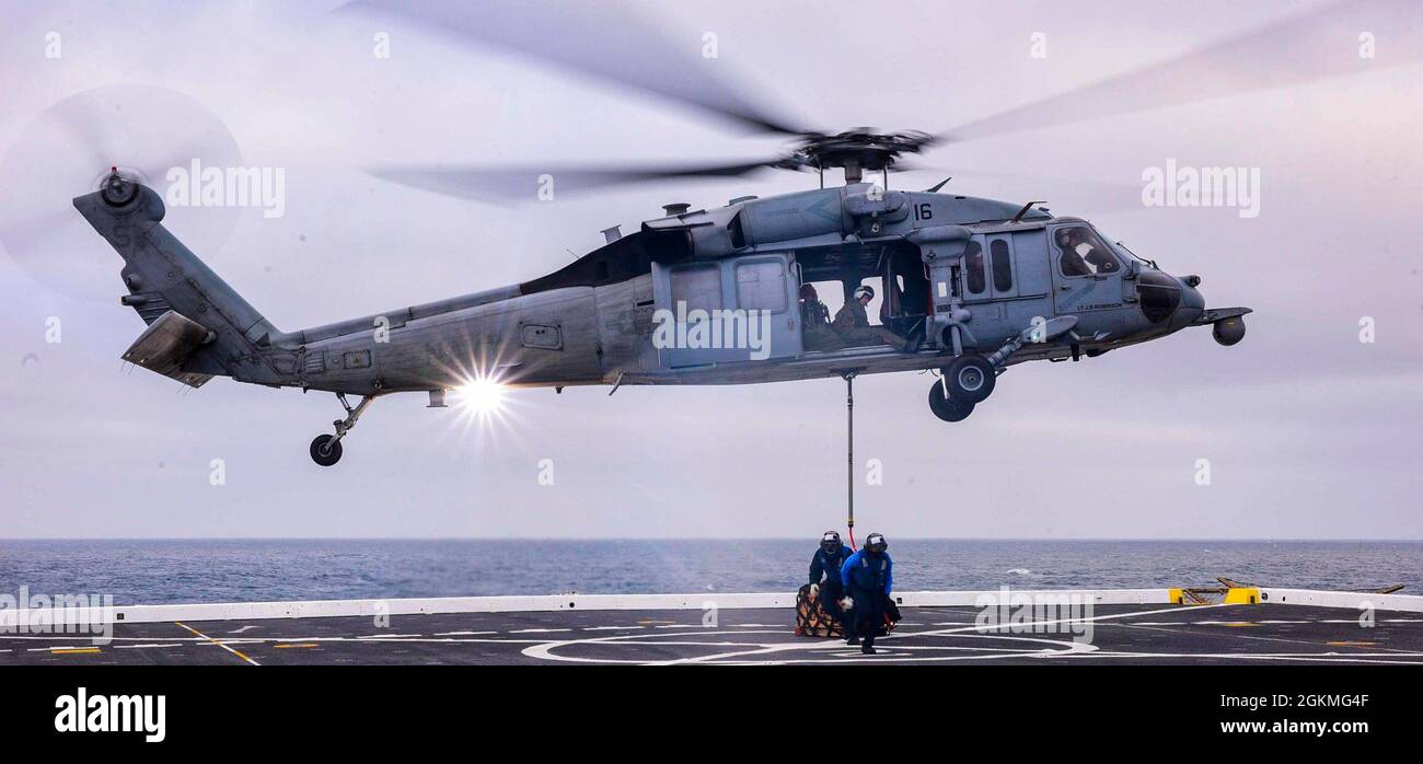 210526-N-MT581-2529 PAZIFISCHER OZEAN (Mai. 26, 2021) ein an das Helicopter Sea Combat Squadron (HSC) 3 angeschlossener Seehawk SH-60s bereitet sich auf den Aufstieg mit Fracht als Teil eines vertikalen Nachschubschiffs auf See an Bord des amphibischen Transportschiffes USS John P. Murtha (LPD 26), Mai 26 vor. John P. Murtha führt derzeit Routineoperationen in der dritten US-Flotte durch. Stockfoto