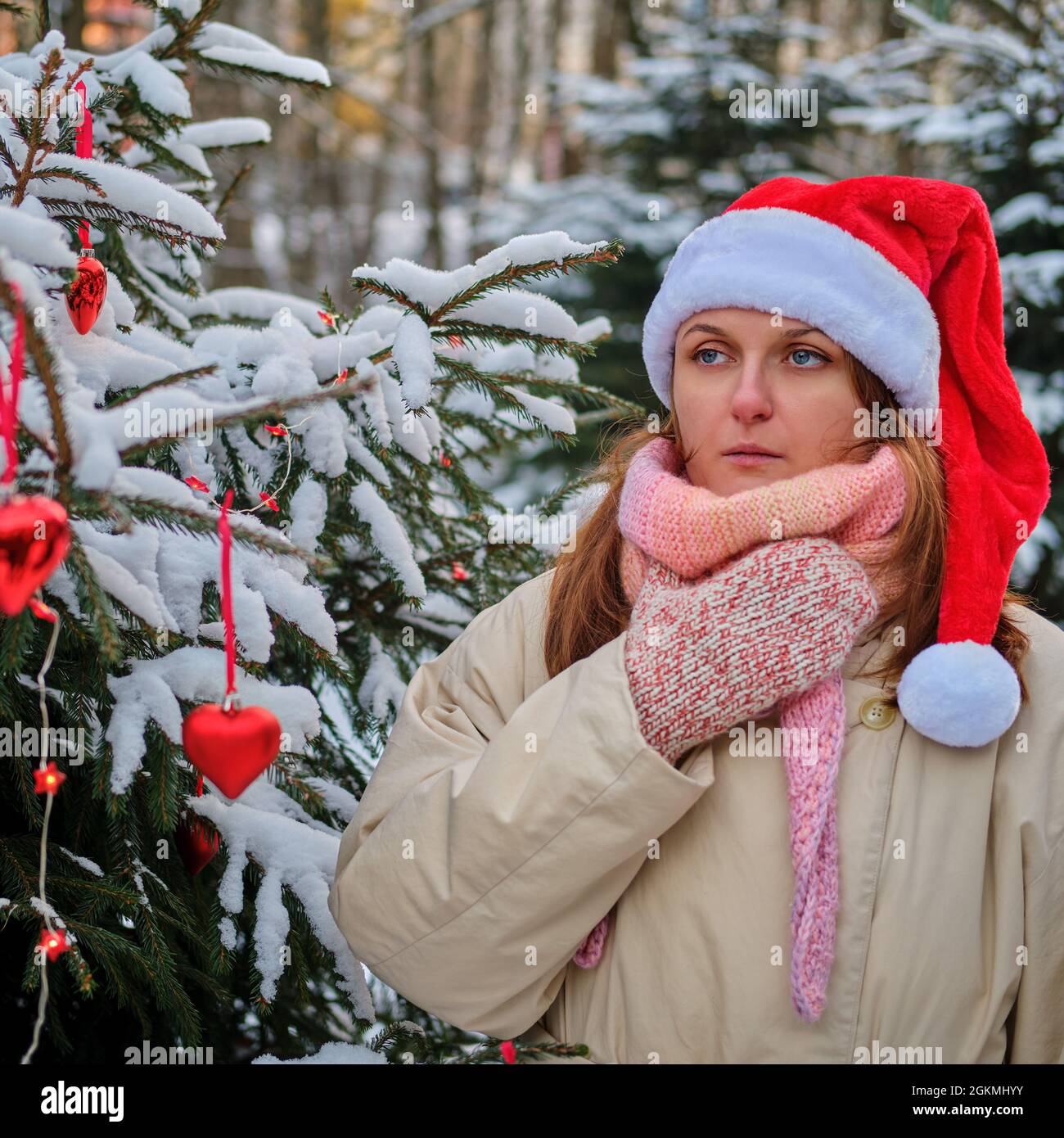 Eine Frau hustet und hält in der Winternatur am Silvesterabend Halsschmerzen an einem Weihnachtsbaum Stockfoto