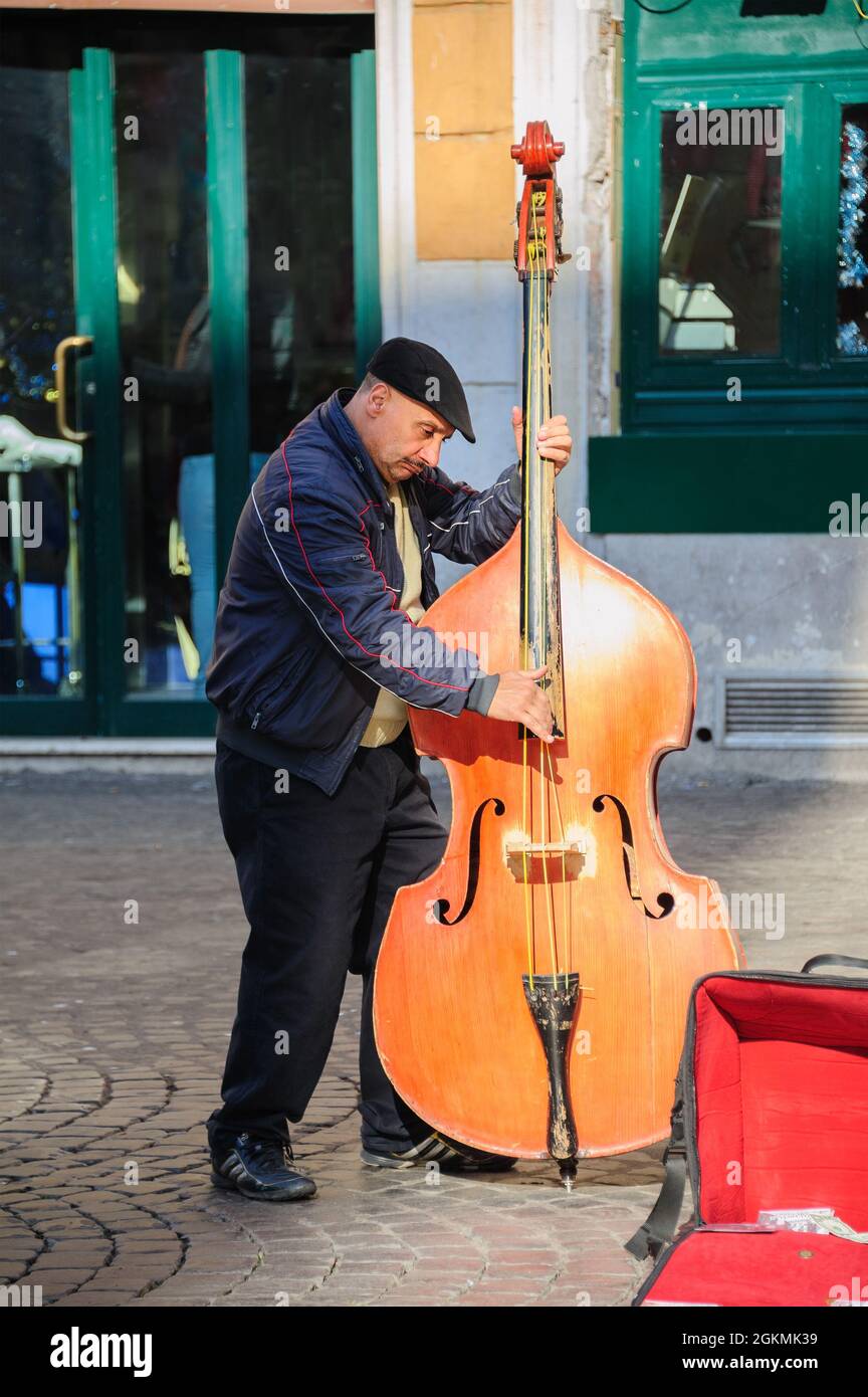 Rom, Italien - 01. Januar 2013: Ein Straßenmusiker spielt Kontrabass in der Nähe von Santa Cecilia in der Kirche von Trastevere, um Tipps zu geben und sein Lied auf CD zu promoten. Stockfoto