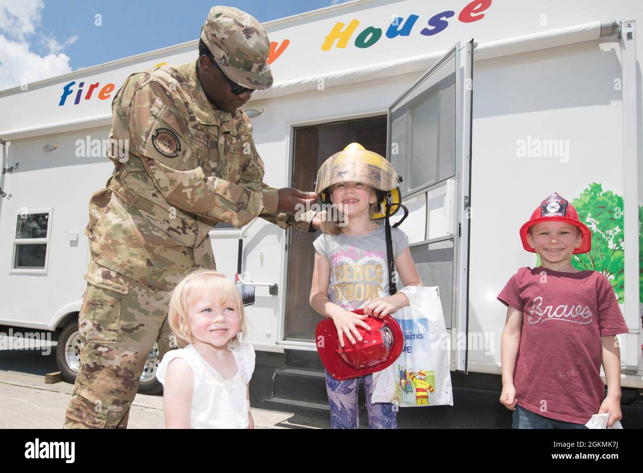 Personal Sgt. Marcus Scriven, der Leiter der 436. Zivilingenieur-Schwadron-Crew, setzt Emma Peterson während der 2021 auf der Dover Air Force Base, Delaware, 27. Mai 2021, stattgefundenen „Sturmblockparty“ einen Feuerwehrhelm auf. Die vom 436. CES Emergency Management Flug gesponserte Blockparty bot den Teilnehmern nützliche Informationen zu schweren Stürmen und Hurrikanen. Stockfoto