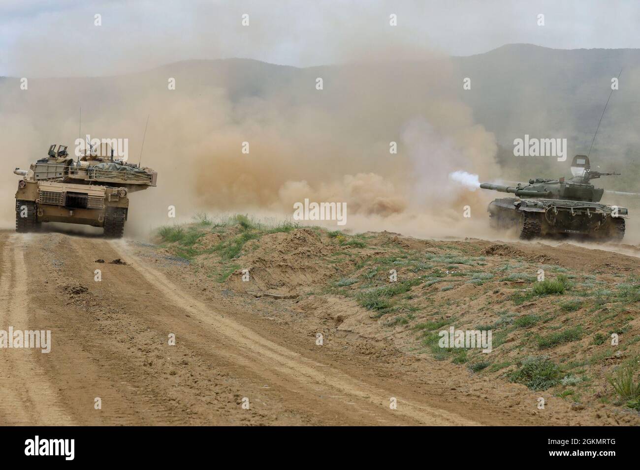 NOVO SELO TRAININGSBEREICH, Bulgarien – Ein Kampfpanzer der bulgarischen Streitkräfte T-72 feuert bei einer Live-Feuerübung zur Unterstützung von Sabre Guardian auf der Novo Selo Trainingsanlage am 30. Mai 2021 zusammen mit einem Panzer der US-Armee M1A2 Abrams auf sein Ziel. Sabre Guardian 21 ist eine verknüpfte Übung von DEFENDER-Europe 21. DEFENDER-Europe 21 ist eine groß angelegte Übung unter Führung der US-Armee, die darauf ausgelegt ist, Bereitschaft und Interoperabilität zwischen den USA, NATO-Verbündeten und Partnermilitärs aufzubauen. In diesem Jahr werden mehr als 28,000 multinationale Streitkräfte aus 26 Nationen nahezu simultan Operationen über mehr als 30 Tr durchführen Stockfoto