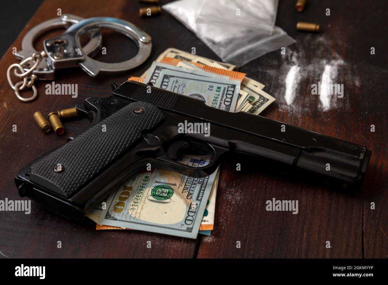 Drogenschmuggel und -Handel, Handschellen, Pistolengeld und Kokainpakete auf Holztischhintergrund. Handel mit illegalen Substanzen und Verhaftung Stockfoto