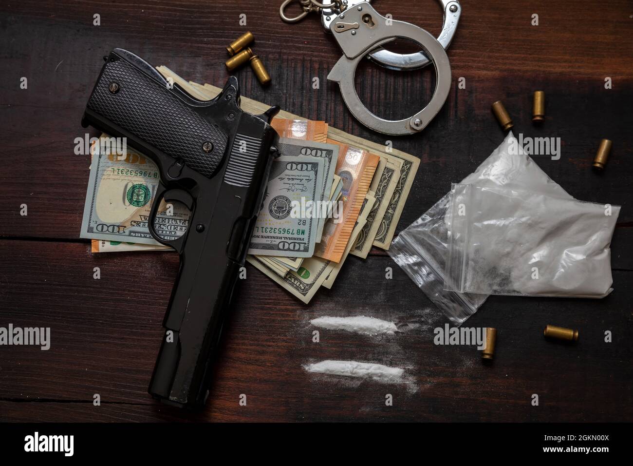 Handel mit illegalen Substanzen und Verhaftung. Handschellen, Pistolengeld und Kokainpakete auf Holztischhintergrund. Drogenschmuggel und -Handel überziehen Stockfoto
