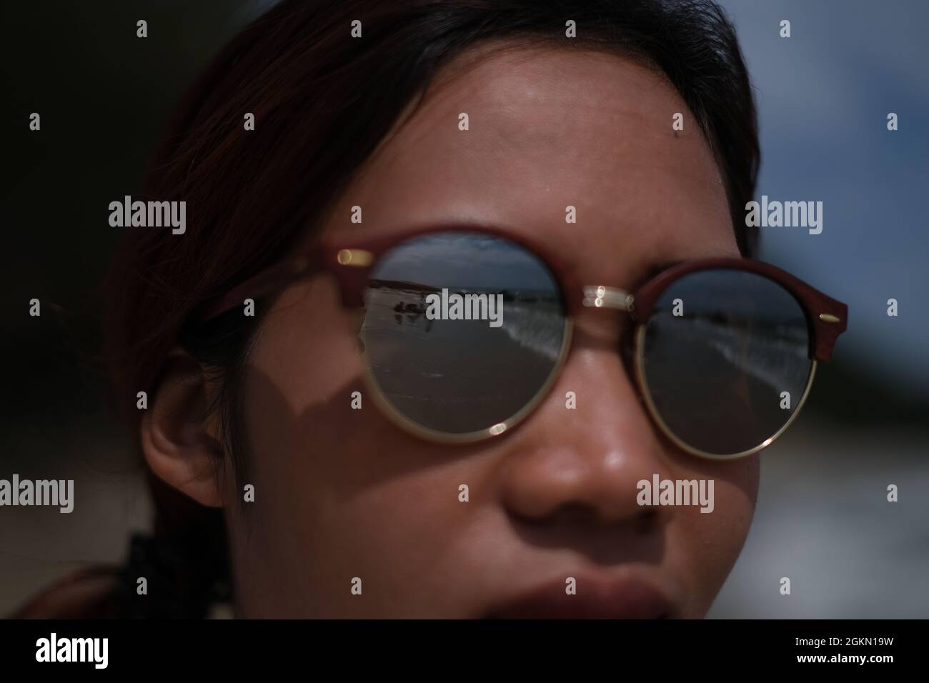 Meer, Strand und Menschen spiegeln sich in der asiatischen Frauensonnenbrille wider Stockfoto
