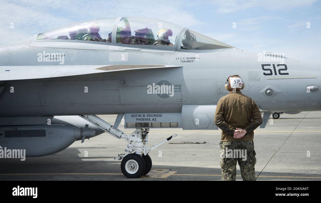 Ein Kapitän der US-Marine führt Piloten der US-Luftwaffe an Bord eines EA-18G Growlers zur Start- und Landebahn auf der Naval Air Station Whidbey Island, Washington, 3. Juni 2021. Piloten von NAS Whidbey Island und dem Luftwaffenstützpunkt Mountain Home nehmen an einer Trainingsmission mit geringem Profil Teil. Stockfoto