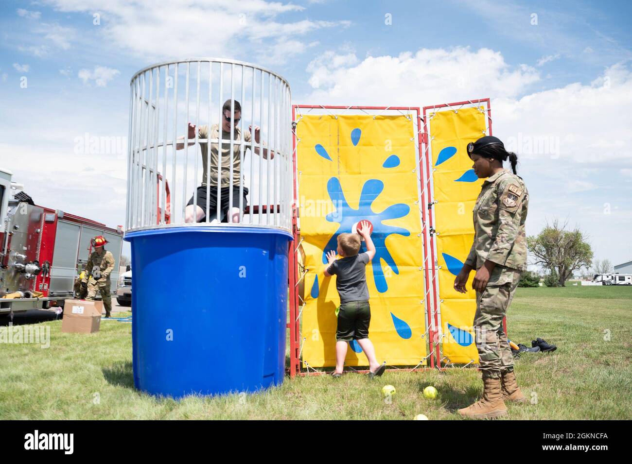 Maj. Derek Tosie, links, Kommandant der 341. Sicherheitskräfte-Geschwader wird von Luke Elliott, dem Sohn des Stabs Sgt, in einen Panzer übertüncht. Brandon Elliott, 741st Missile Security Forces Squadron Field Security Controller, während Airman 1st Class Veasia Shavers, 341st SFS Installation Patrolman, Uhren Juni 4, 2021 auf dem Luftwaffenstützpunkt Malmstrom, Month. Der Dunk-Tank war Teil eines Bike-Safety-Rodeos, das vom 341. SFS in Zusammenarbeit mit der lokalen Gemeinde veranstaltet wurde. Stockfoto