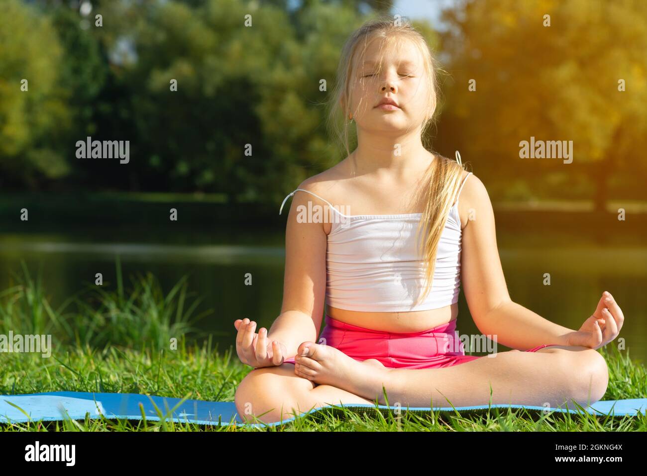 Kleine süße kaukasische Mädchen üben Yoga-Pose auf Matte im Park, Gesundheit und Bewegung Konzept. Stockfoto