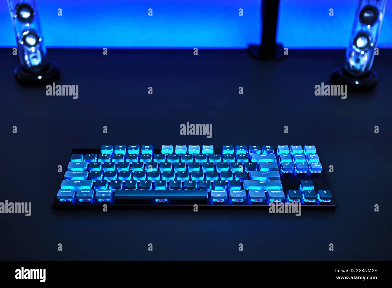 Computerschreibtisch mit heller hinterleuchteter Tastatur und Stereolautsprechern. Blaues Farbdesign. Professionelle Computerspiel spielen, eSport Business und online w Stockfoto