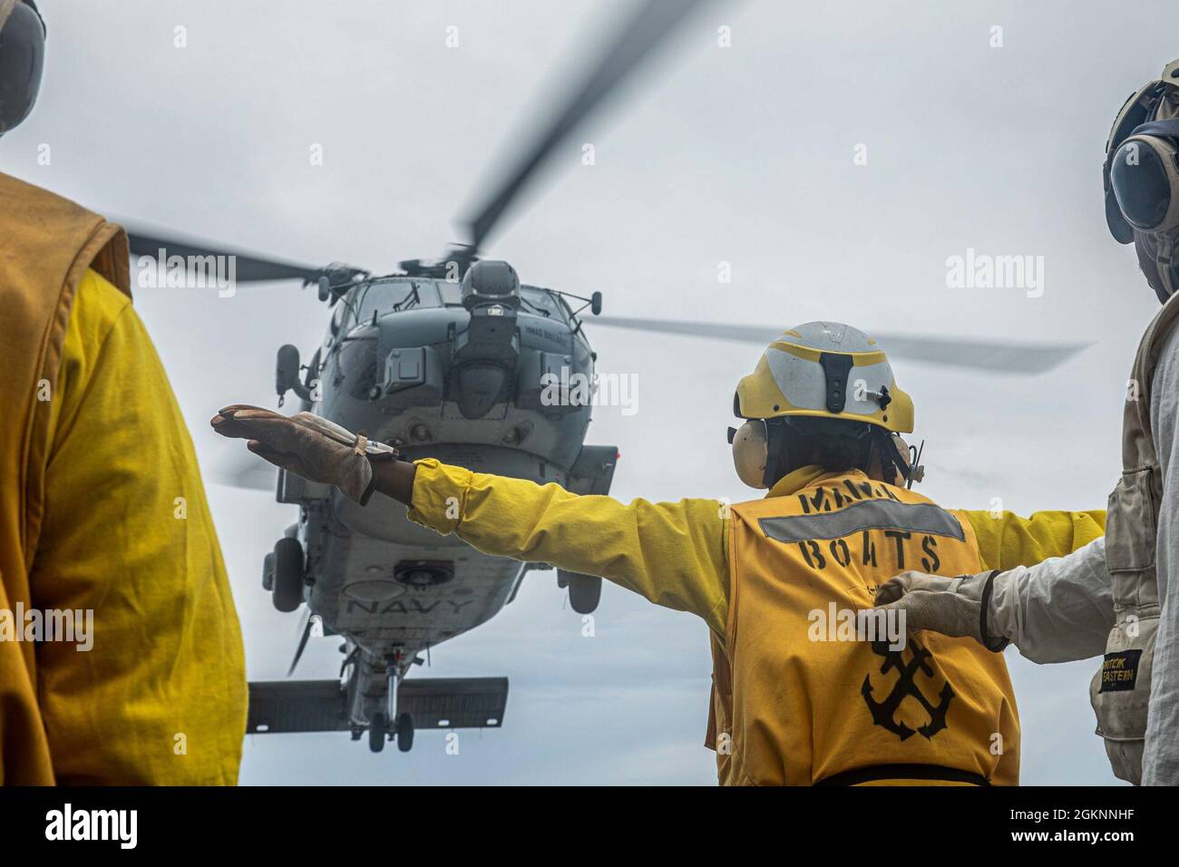 210607-N-XU073-1324 SÜDCHINESISCHES MEER (7. Juni 2021) – Seeleute an Bord der USS Curtis Wilbur (DDG 54) der Arleigh Burke-Klasse signalisieren einen MH-60R Sea Hawk, der der Royal Australian Navy Anzac-Klasse HMAS Ballarat (FFH 155) auf dem Flugdeck zugewiesen wurde. Curtis Wilbur ist Kommandant der Task Force 71/Destroyer Squadron (DESRON) 15, der größten vorwärtseingesetzten DESRON der Marine und der wichtigsten Surface Force der 7. US-Flotte. Stockfoto