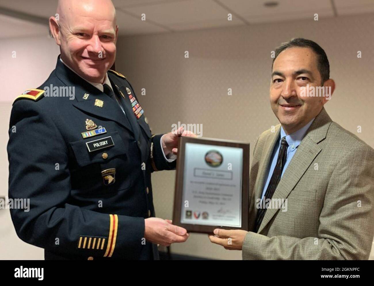 Armeeoberst Kevin Polosky, stellvertretender Stabschef für Operationen beim U.S. Army Sustainment Command, überreicht David Saenz, dem Chef der Pläne und Operationen im Logistikzentrum Bayern der 405. Armee-Feldunterstützungsbrigade, seine Abschlussurkunde. Saenz und 12 weitere AMC-Mitarbeiter haben kürzlich den Journey to Leadership Level III abgeschlossen. Das JLT-Programm dient der Vorbereitung potenzieller zukünftiger Führungskräfte auf Schlüsselpositionen durch Übersichten über die Aufgaben, den Kontakt mit Führungskräften, Coaching und Networking. Stockfoto