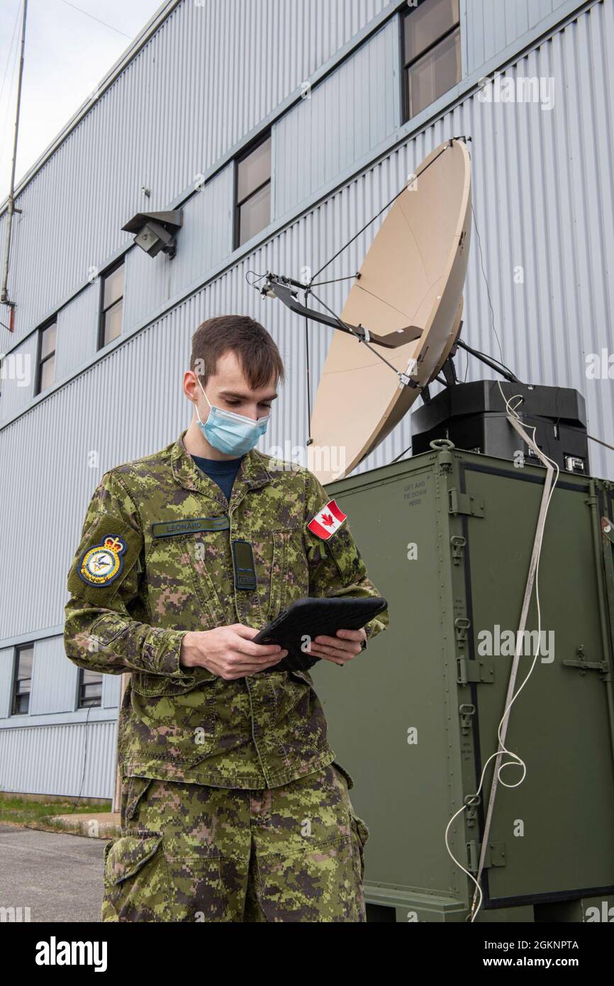 AVR Marc-Antoine Leonard überprüft die Konnektivität der FA-240 Satellitenantenne mit einem Tablet nach der Installation der Antenne während der EX. AMALGAM DART 21-1 im 5. Hangar in 5 Wing Goose Bay, Happy Valley, NFLD und Labrador am Dienstag, den 8. Juni 2021. 2021 DND/MDN. EX-AMALGAM DART 21-1. Stockfoto