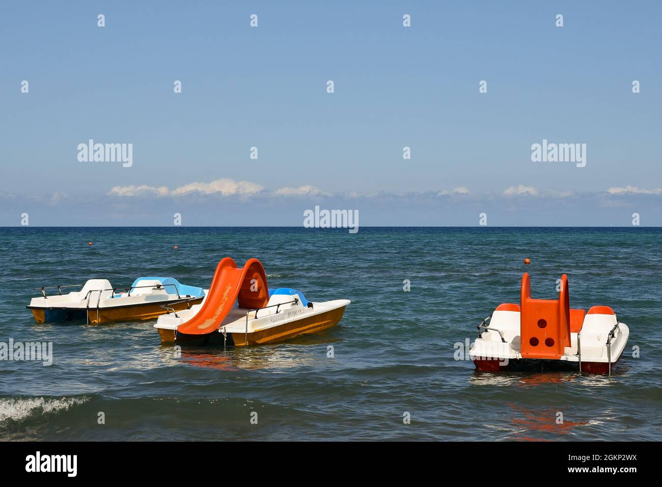 Drei bunte Tretboote ankerten an einem sonnigen Sommertag am Ufer des toskanischen Meeres, Marina di Castagneto Carducci, Livorno, Toskana, Italien Stockfoto