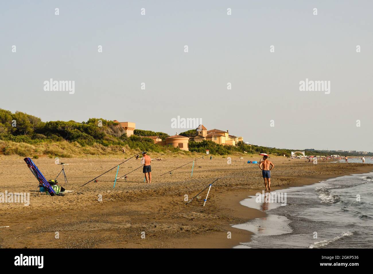 Ein Fischer, der im Sommer Angelruten am Sandstrand der toskanischen Küste der Maremma vorbereitet, Marina di Castagneto Carducci, Livorno, Toskana, Italien Stockfoto