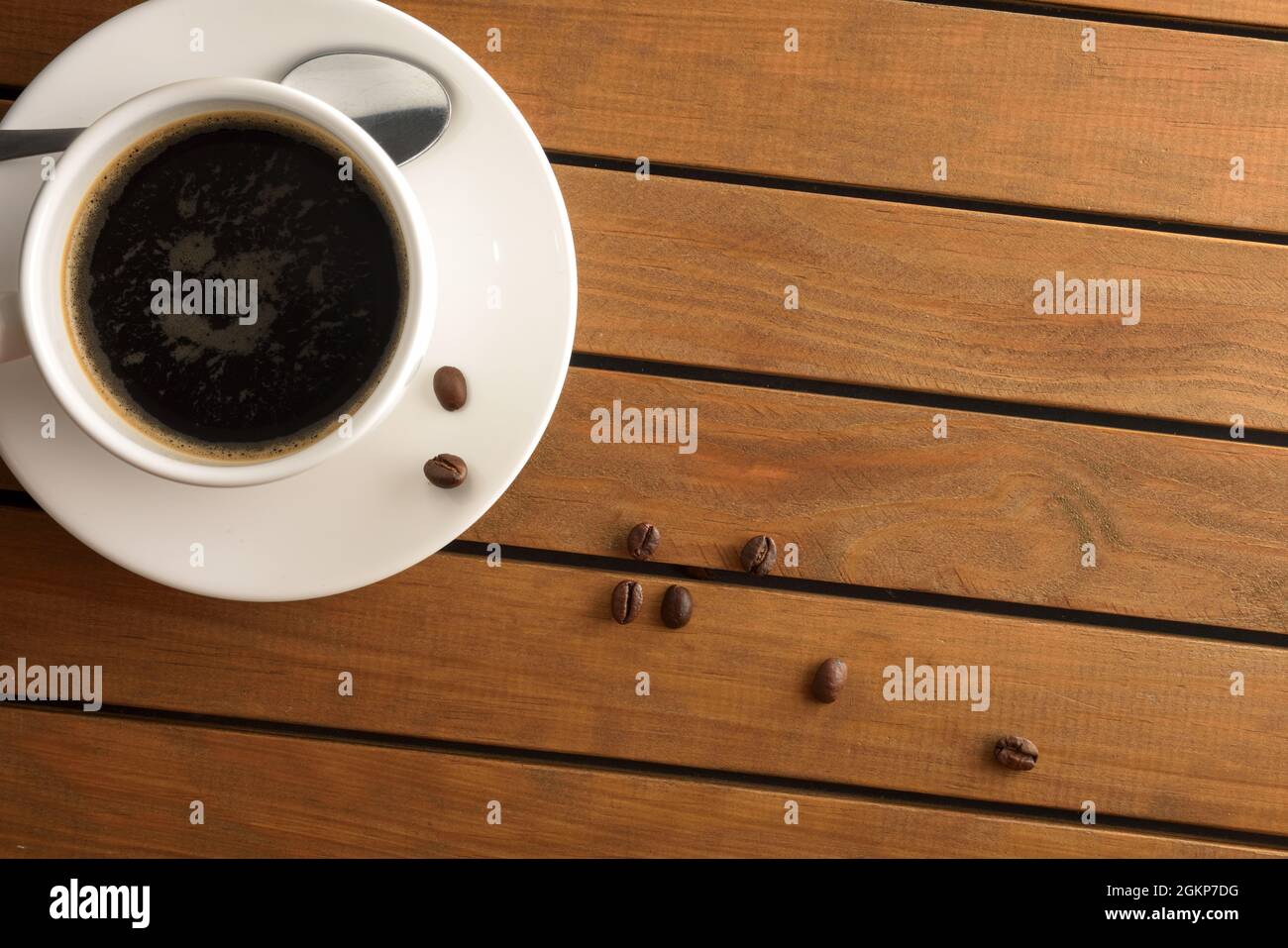 Weiße Porzellanbecher mit heißem Kaffee auf Holzlattentisch und Bohnen-Detail. Draufsicht. Horizontale Zusammensetzung. Stockfoto
