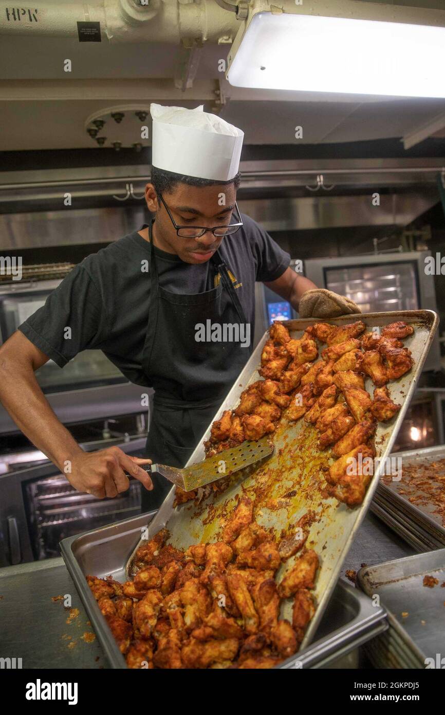 Der kulinarische Spezialist Seaman Laquouan Jefferson aus Baltimore, der der Versorgungsabteilung von USS Gerald R. Ford (CVN 78) zugewiesen wurde, bereitet Essen in Fords Achtergalle zu, 12. Juni 2021. Ford führt derzeit im Atlantik Full Ship Shock Trials (FSST) durch. Die US Navy führt Schockversuche an neuen Schiffsdesigns mit Live-Sprengstoffen durch, um zu bestätigen, dass unsere Kriegsschiffe auch unter den harten Bedingungen, die sie im Kampf treffen könnten, weiterhin anspruchsvolle Missionsanforderungen erfüllen können. Stockfoto