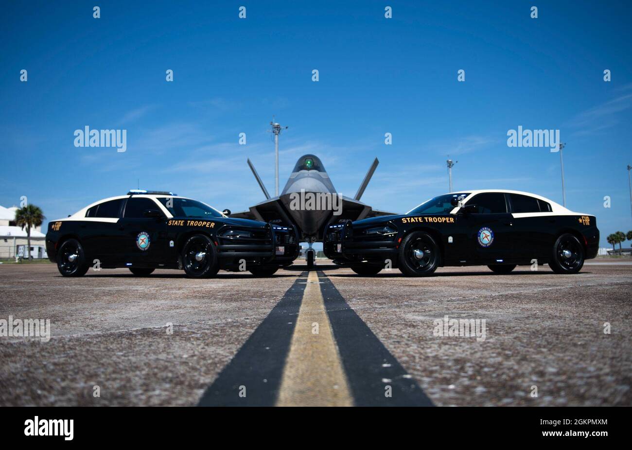 Zwei Florida Highway Patrol Fahrzeuge werden vor einem F-22 Raptor auf der Tyndall Air Force Base, Florida, 14. Juni 2021 gestellt. Die FHP teilt sich die gemeinsame Zuständigkeit mit der 325. Sicherheitskräfte-Staffel, da sie eng zusammenarbeiten, um die integrierte Verteidigung entlang des US-Highway 98 aufrechtzuerhalten. Stockfoto