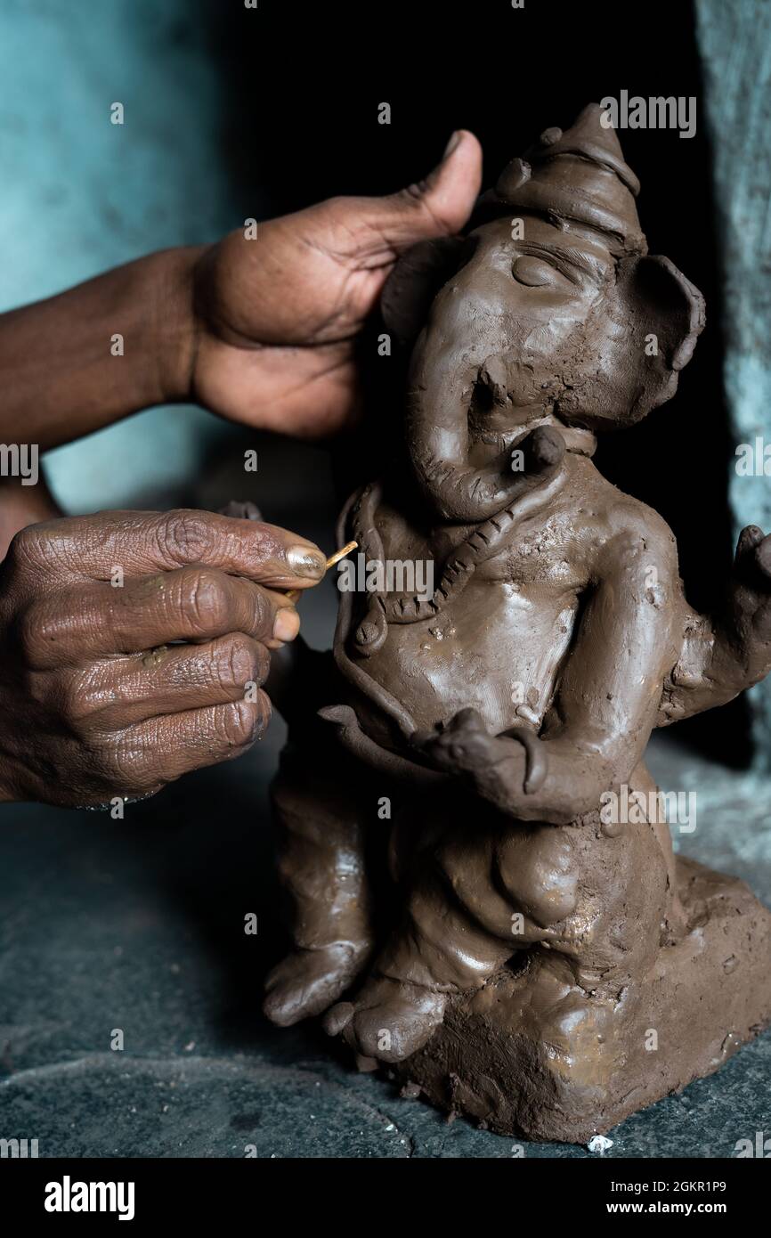 Nahaufnahme von Künstlerhänden, die das ganesh-Idol für das ganesha-Fest machen - Konkpet der Vorbereitungen für religiöse Feste Stockfoto