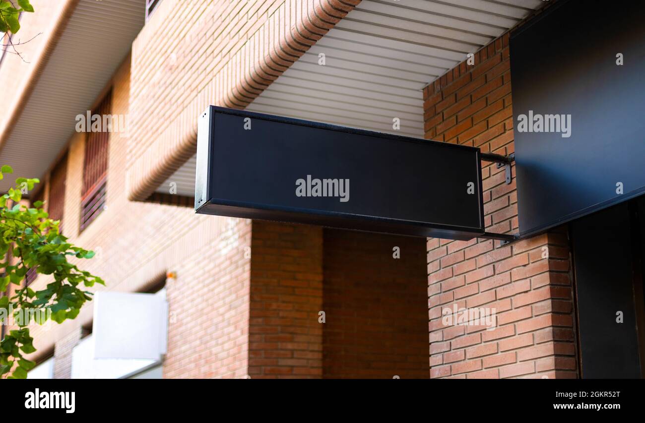 Schwarzes kommerzielles Schild mit Platz für ein Modell für Branding-Design an einer Ladenwand auf der Straße Stockfoto