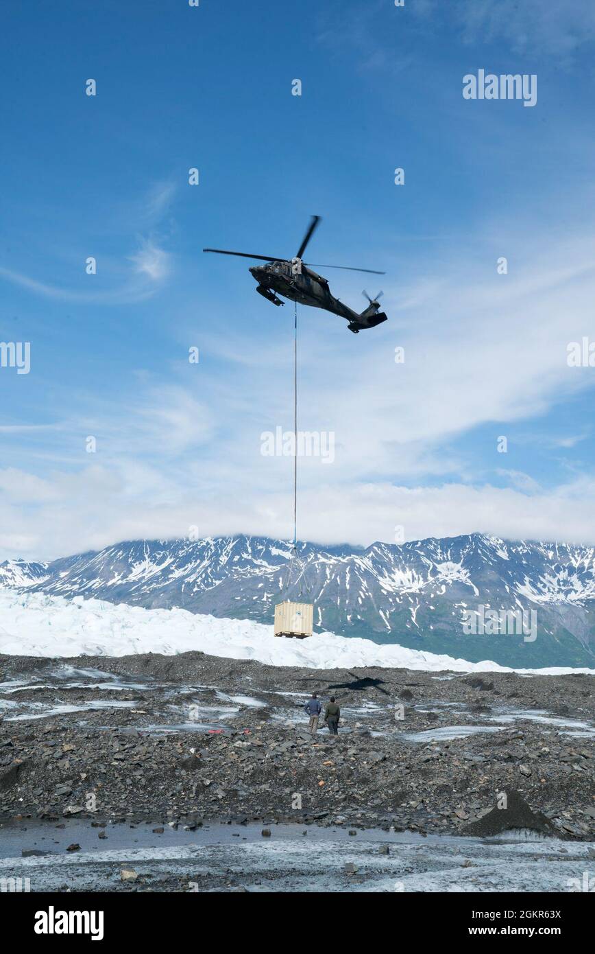 Ein Hubschrauber der Alaska Army National Guard UH-60 Black Hawk bewegt einen Container auf dem Colony Glacier, Alaska, 17. Juni 2021. Die Operation Colony Glacier ist ein Versuch, die Überreste von Dienstmitgliedern und Wracks eines C-124-Flugzeuges, das im November 1952 mit 52 Militärmitgliedern an Bord gelandet war, zu retten. Die Behälter werden zur Lagerung und zum Transport von Ausrüstung, Resten und Trümmern verwendet, die vom Bergungsteam gefunden wurden. Stockfoto