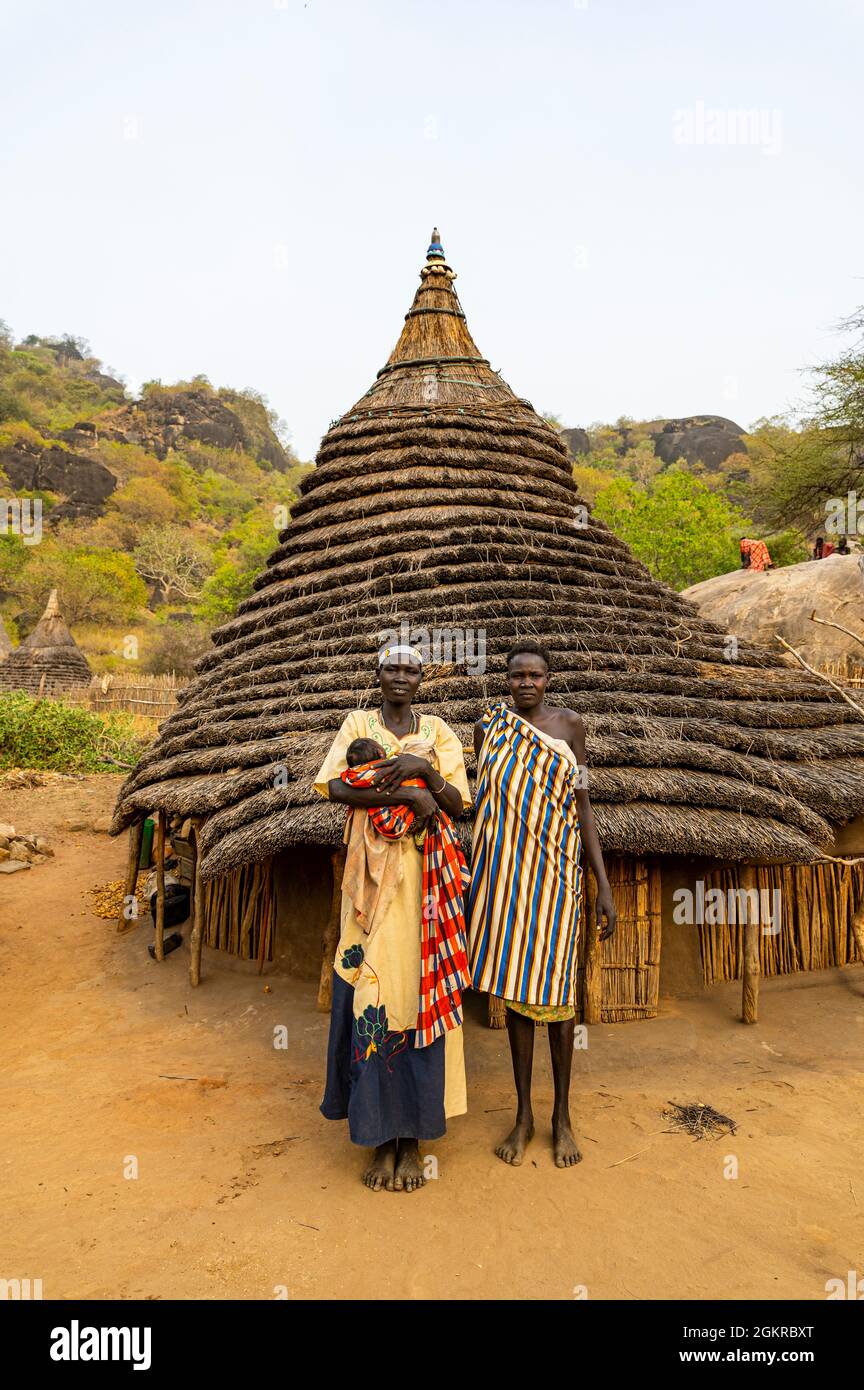 Traditionell gekleidete junge Mädchen aus dem Stamm der Laarim vor ihrer Hütte, Boya Hills, Eastern Equatoria, Südsudan, Afrika Stockfoto