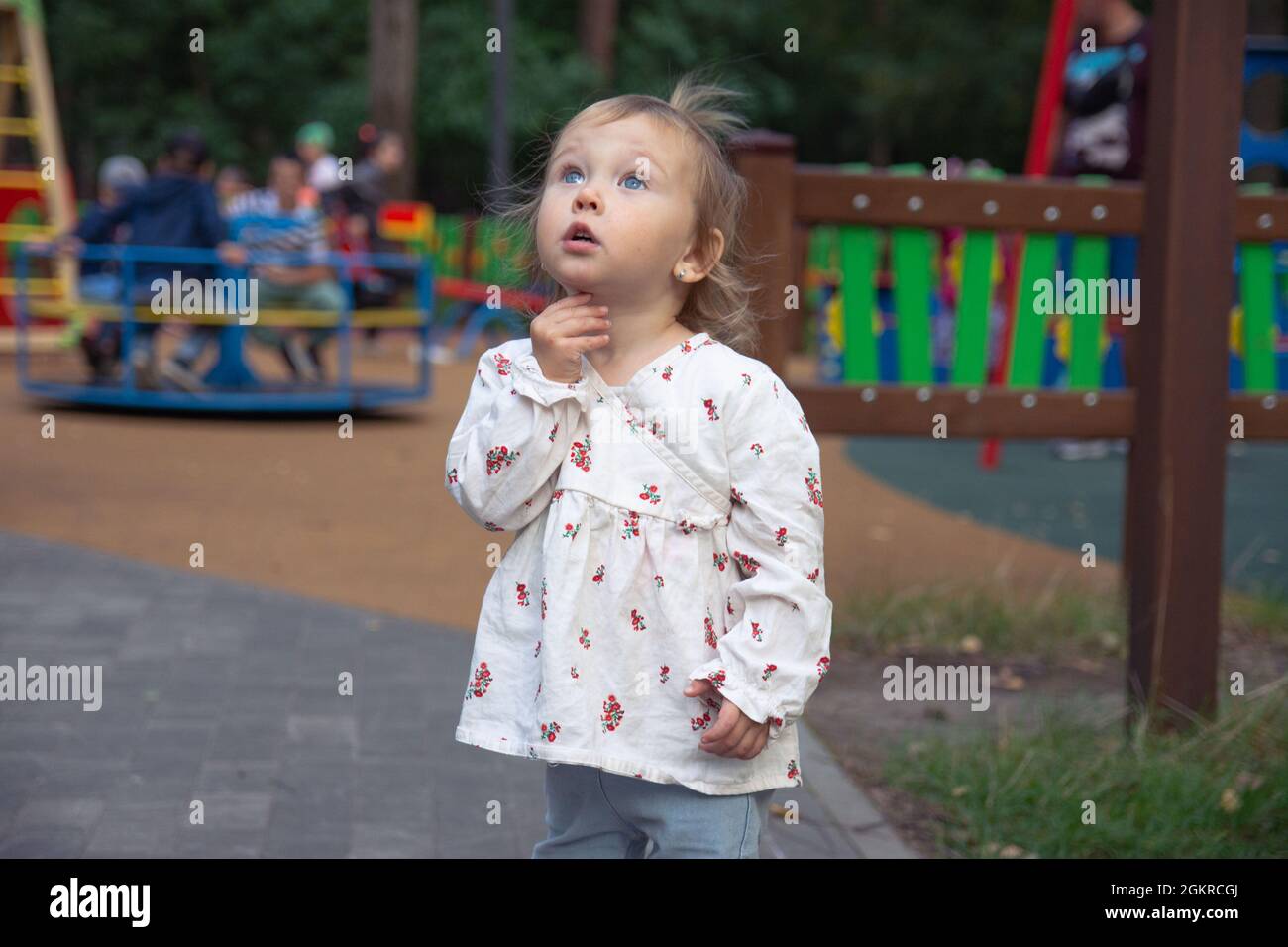 Nette liebenswert kaukasischen kleinen Mädchen spielt auf dem Spielplatz im Freien. Ein Mädchen in einem weißen Kleid und ihre Haare in einem Pferdeschwanz. Stockfoto