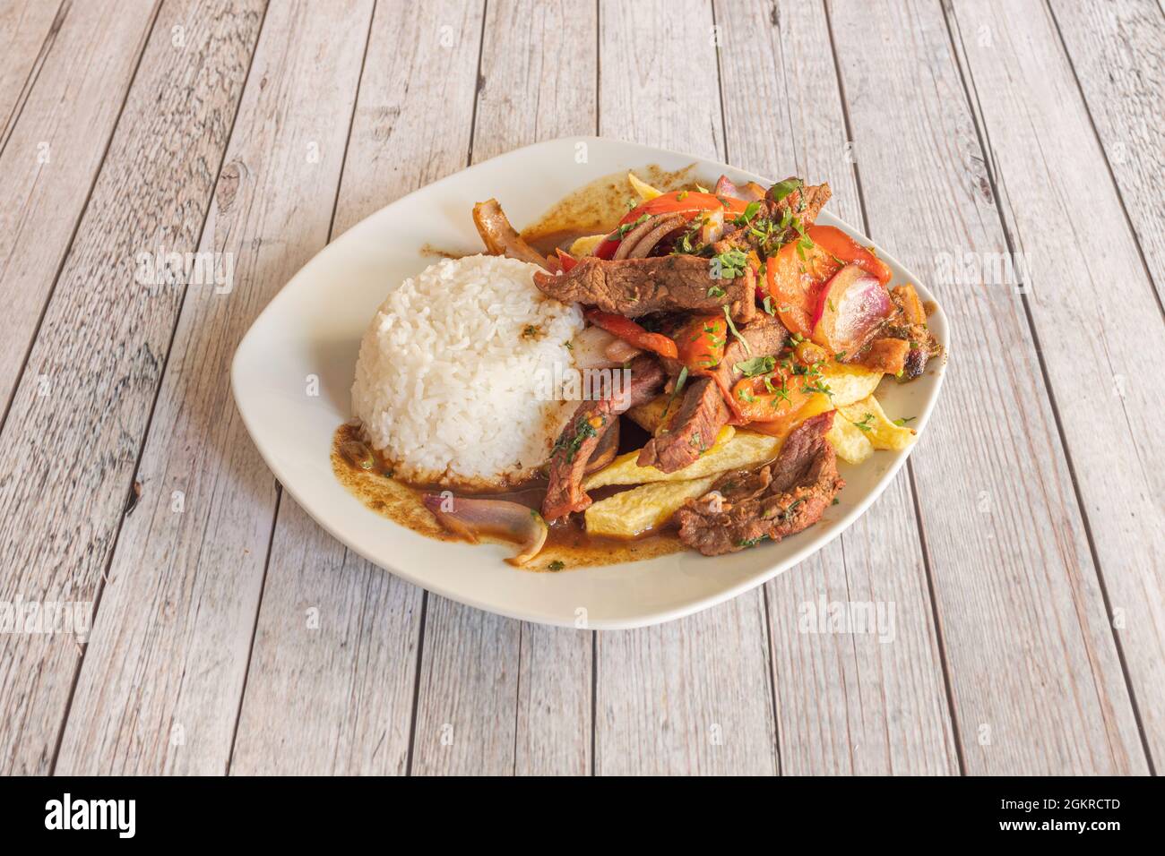 Teller mit gebratenen Filet mit weißem Reis und Sojasauce, Tomaten, roten Zwiebeln, garniert mit hausgemachten Chips Stockfoto