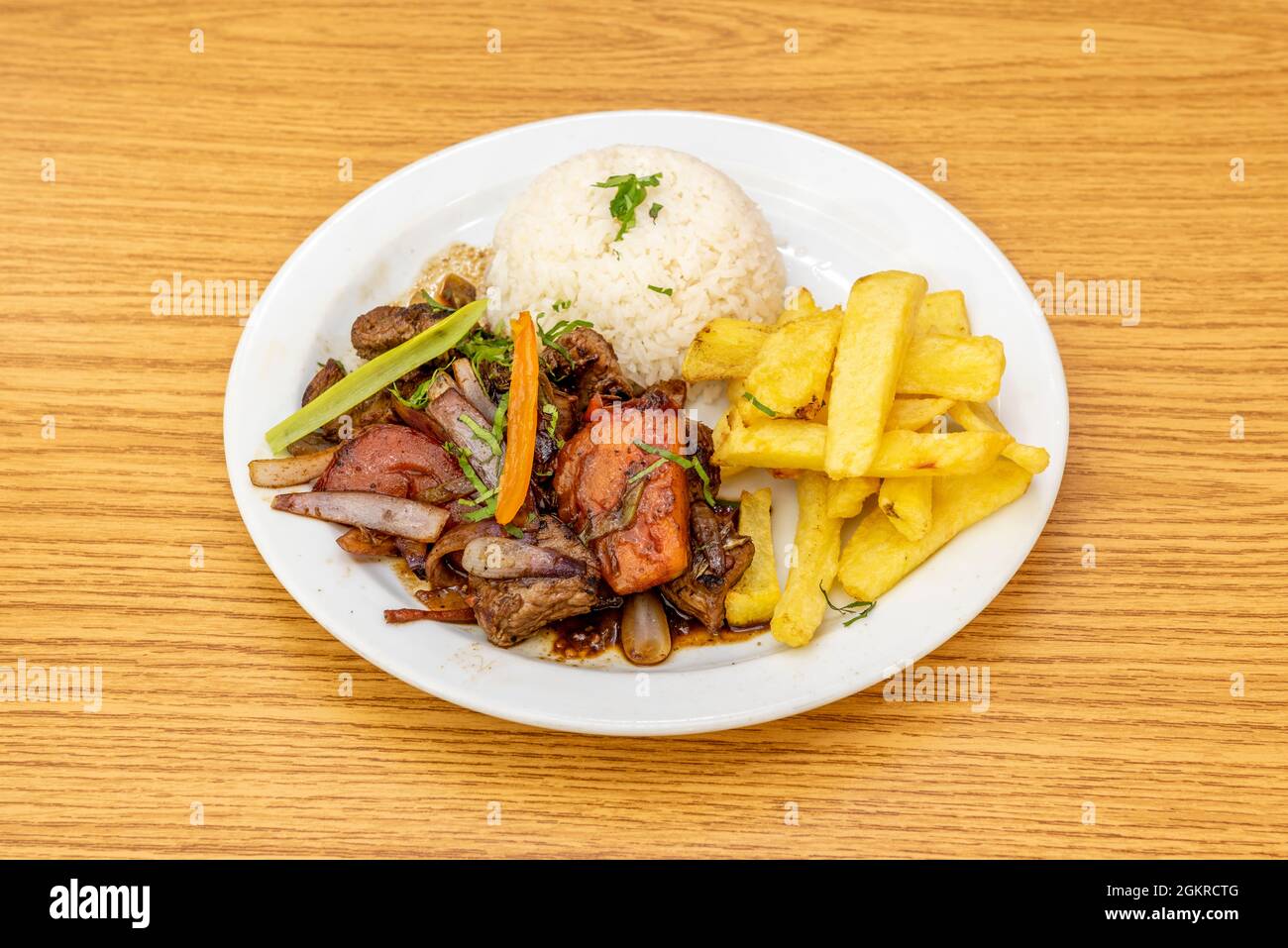 Stilvolle Präsentation eines traditionellen peruanischen Rezepts für gebratenen Filet mit Gemüse, einer Garnierung aus hausgemachten Kartoffeln und einer Schüssel umgedrehtem Stockfoto