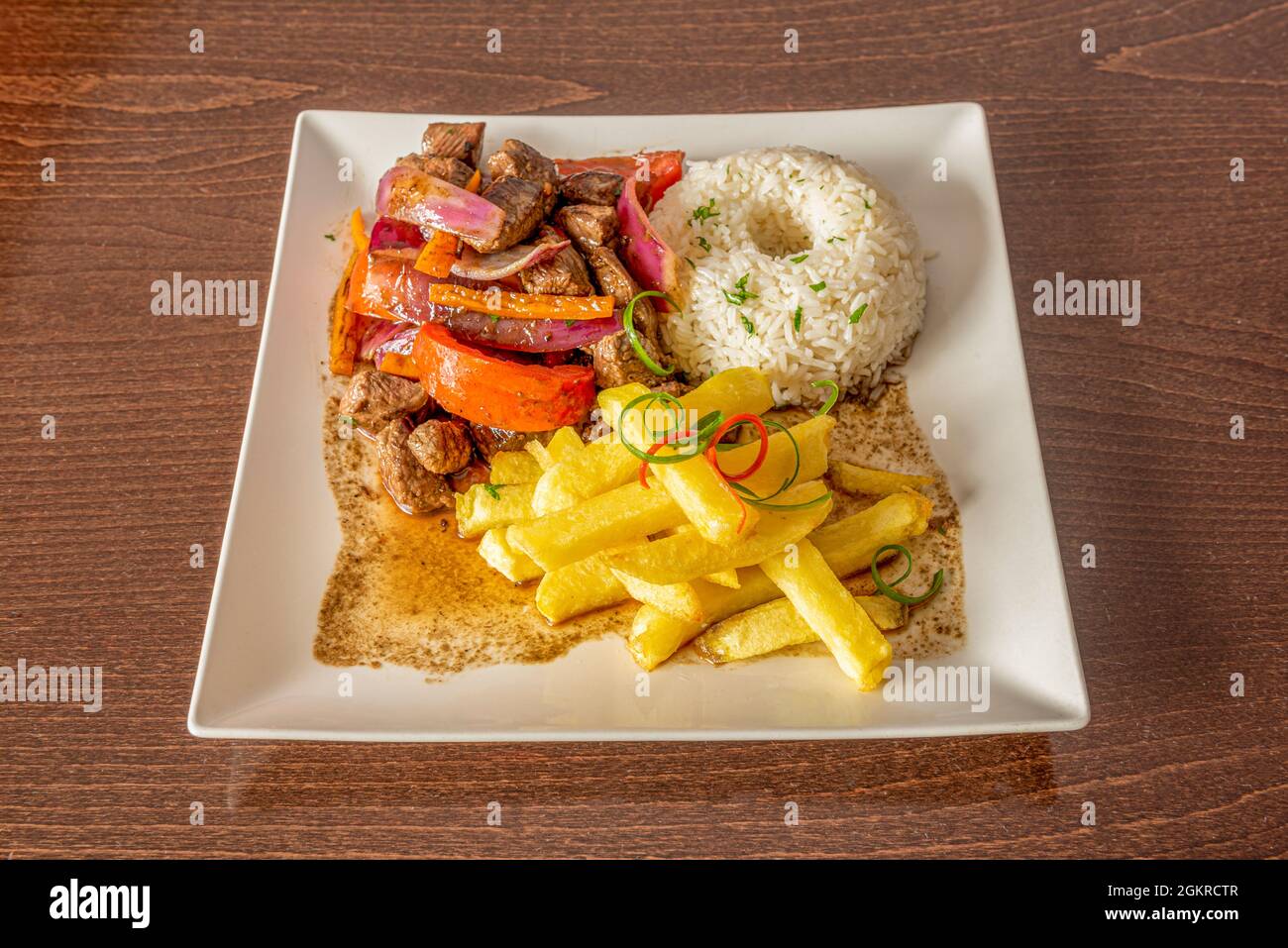 Typisches Rezept von gebratenem Schweinefleisch mit Zwiebeln, Paprika und weißem Reis mit gebratenen Kartoffeln Stockfoto