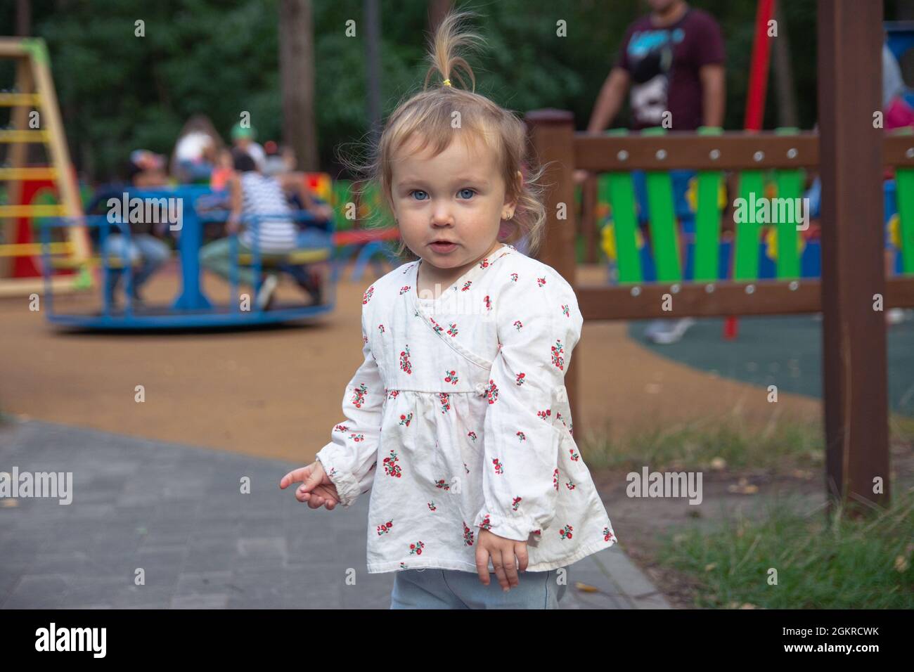 Nette liebenswert kaukasischen kleinen Mädchen spielt auf dem Spielplatz im Freien. Ein Mädchen in einem weißen Kleid und ihre Haare in einem Pferdeschwanz. Stockfoto