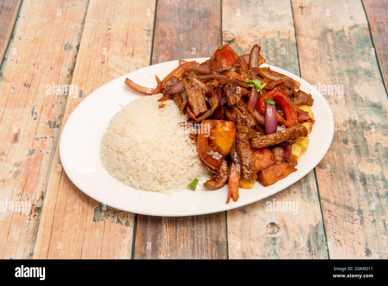 Tablett mit sautiertem Rinderfilet im peruanischen Stil mit einer Garnierung aus hausgemachten Pommes Frites und weißem Reis. Sautes Gemüse, Tomaten, Paprika, rote Zwiebeln, Parsle Stockfoto