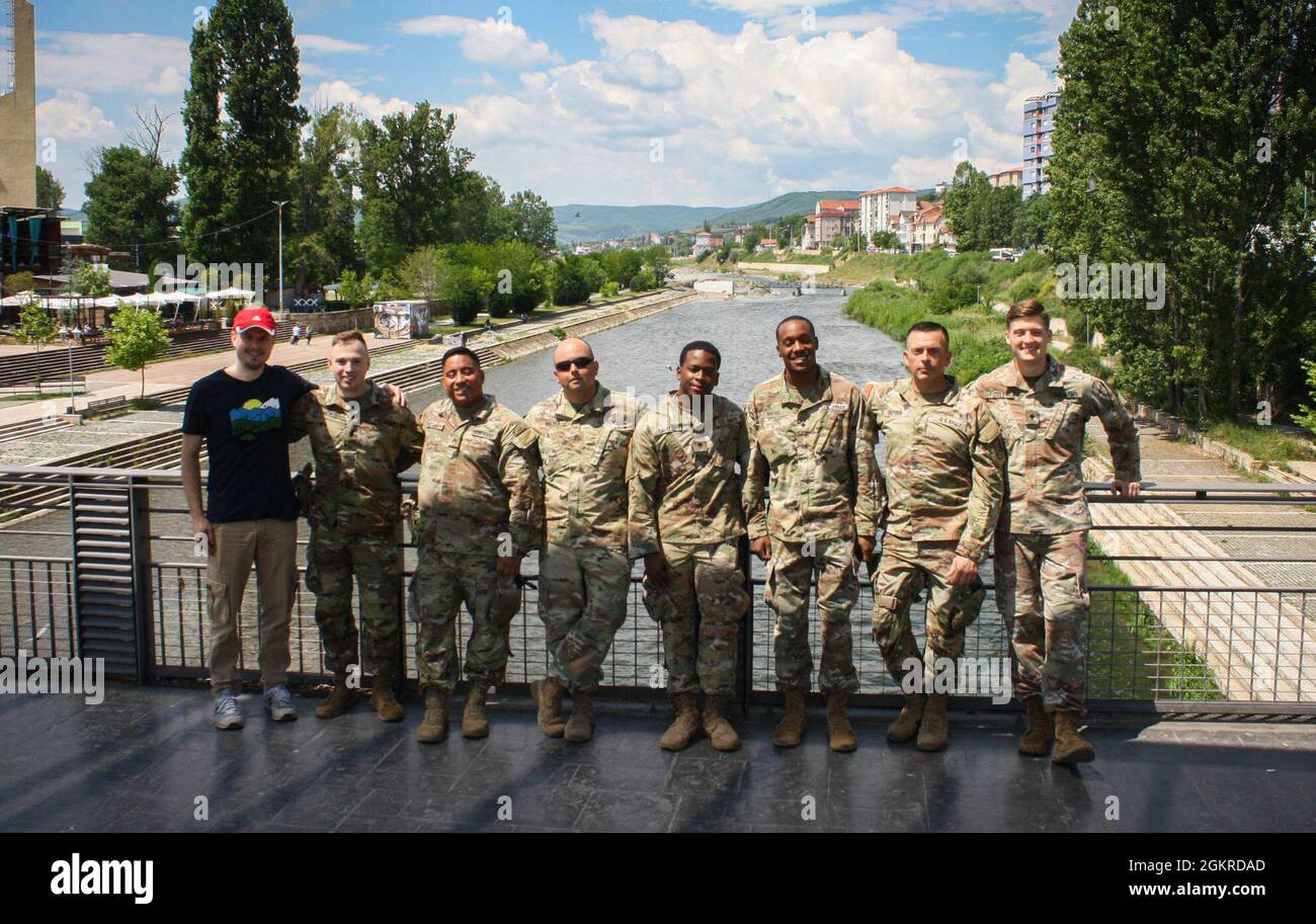 US-Soldaten, die dem Regionalkommando Ost, der Kosovo Force, zugewiesen wurden, und Stefan Kalba, Mitglied des Leuchtturms des Zentrums für lebenslanges Lernen, posieren für ein Gruppenfoto auf einer Brücke in Mitrovica/Mitrovicë, Kosovo, am 19. Juni 2021. Mehr als 40 Menschen halfen freiwillig bei der Säuberung, darunter US-Soldaten und Schweizer Soldaten sowie Bewohner aus Nord- und Süd-Mitrovica/Mitrovicë. Stockfoto