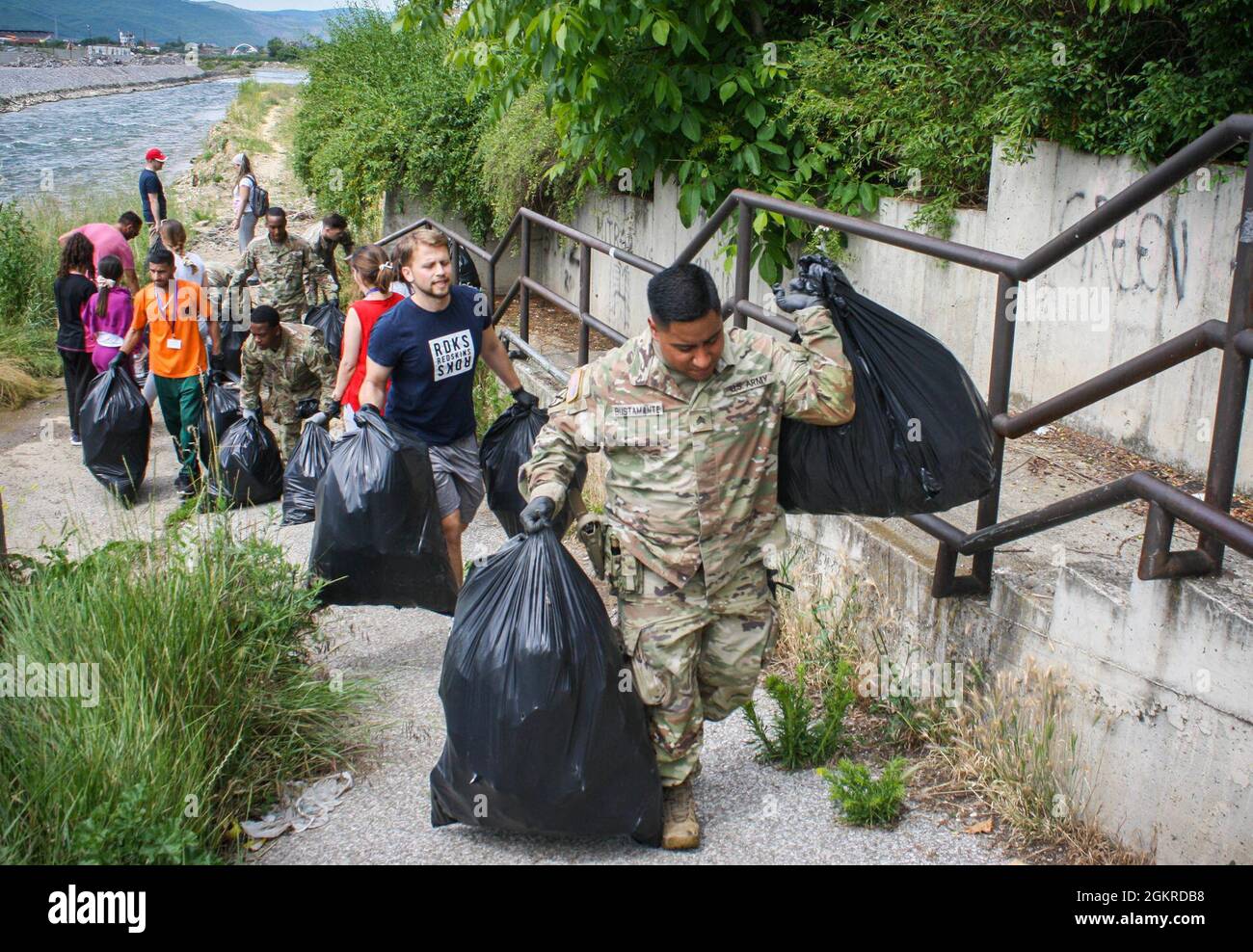Am 19. Juni 2021 tragen US-Soldaten, die dem Regionalkommando Ost, der Kosovo-Streitkräfte und Anwohnern zugewiesen sind, Müllsäcke entlang einer Brücke in Mitrovica/Mitrovicë, Kosovo. Mehr als 40 Menschen halfen freiwillig bei der Säuberung, darunter US-Soldaten und Schweizer Soldaten sowie Bewohner aus Nord- und Süd-Mitrovica/Mitrovicë. Stockfoto