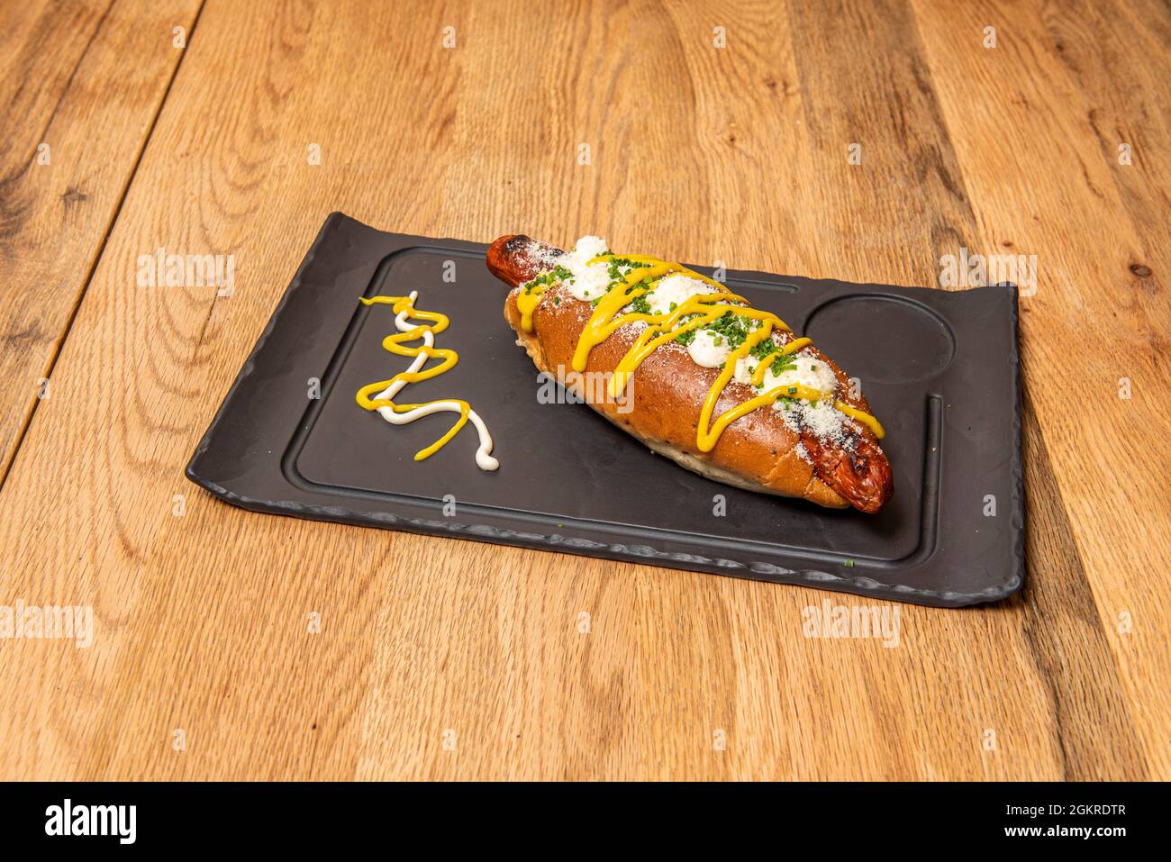Hot Dog mit Frischkäse, geschreddertem Käse, Cheddar-Käse und Schnittlauch mit Mayonnaise Stockfoto